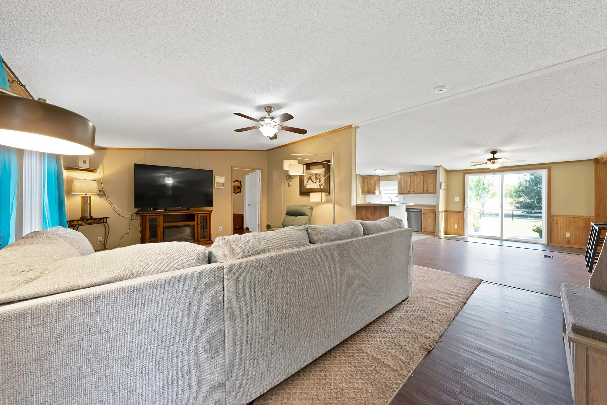 Open-concept layout with wood-finish flooring, a ceiling fan, and sliding glass doors