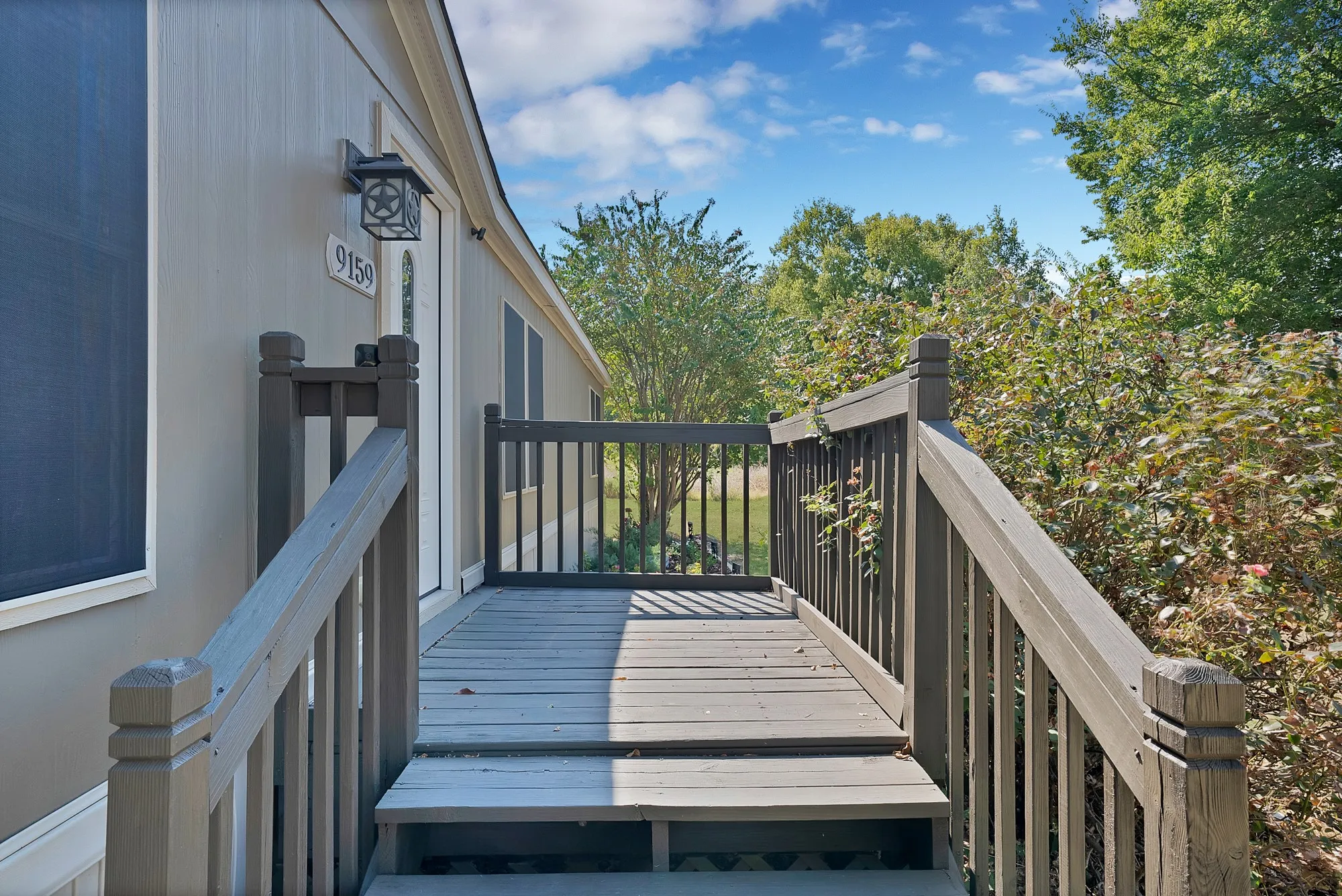 Elevated composite deck with black aluminum railings and balusters, featuring direct access to the home via a covered entry