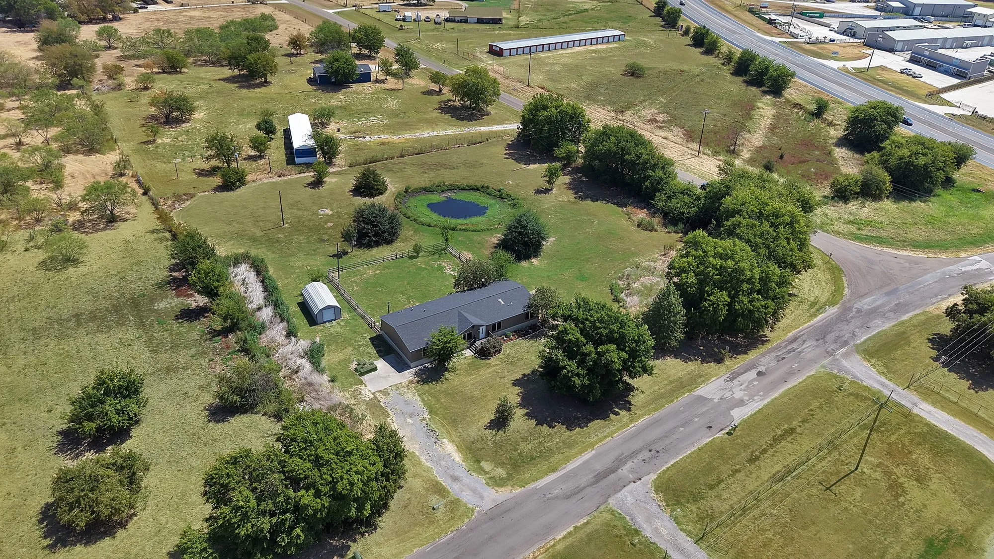Expansive lot with a single-story residence, private pond, detached storage building, and mature trees