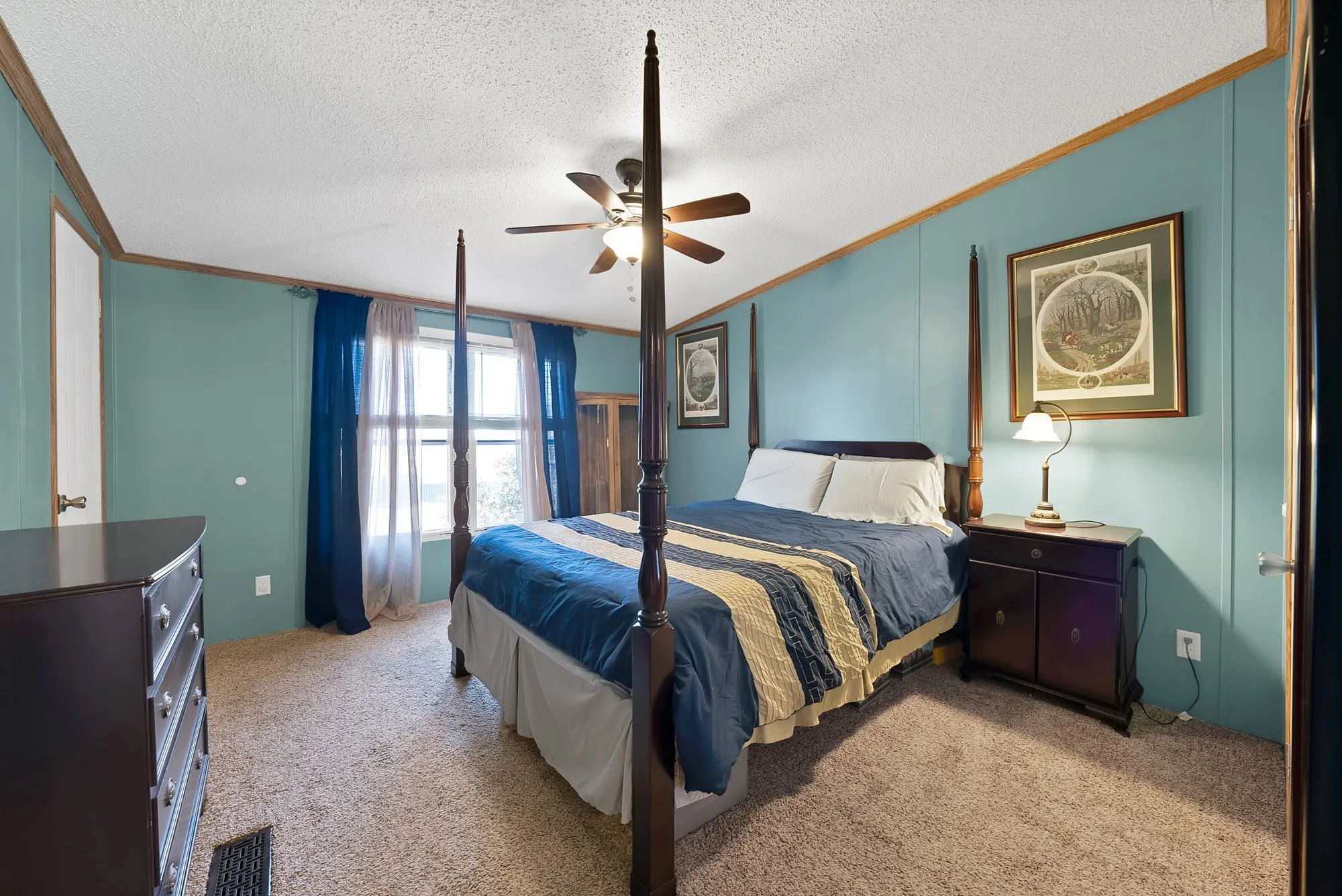 Carpeted room with paneled walls, ceiling fan, and window with curtains