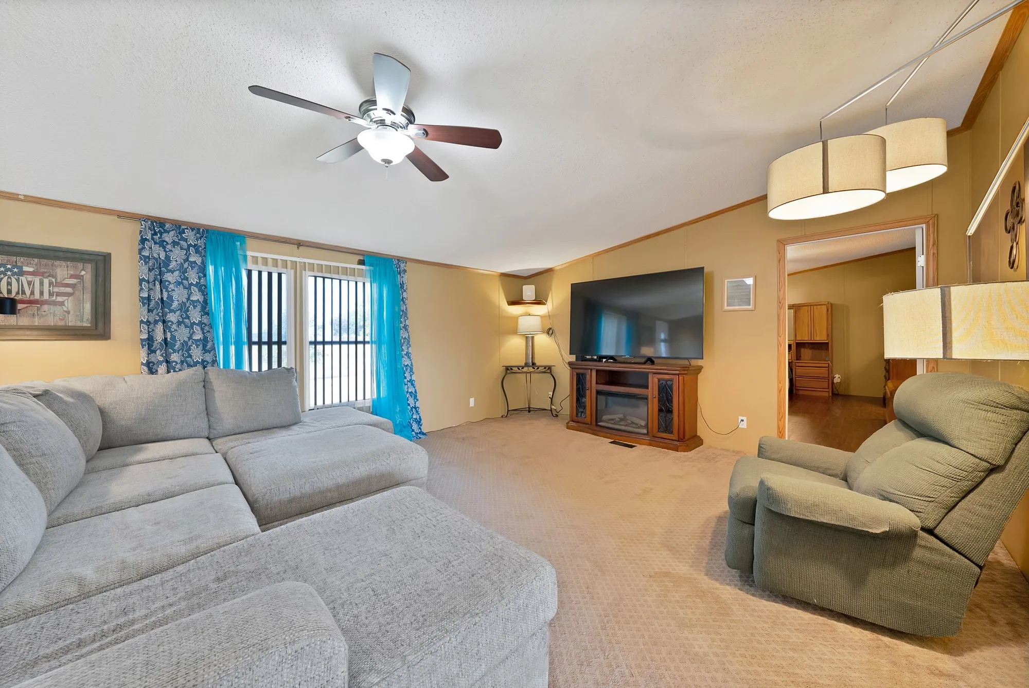 Carpeted living area with ceiling fan, sliding glass doors, and recessed lighting