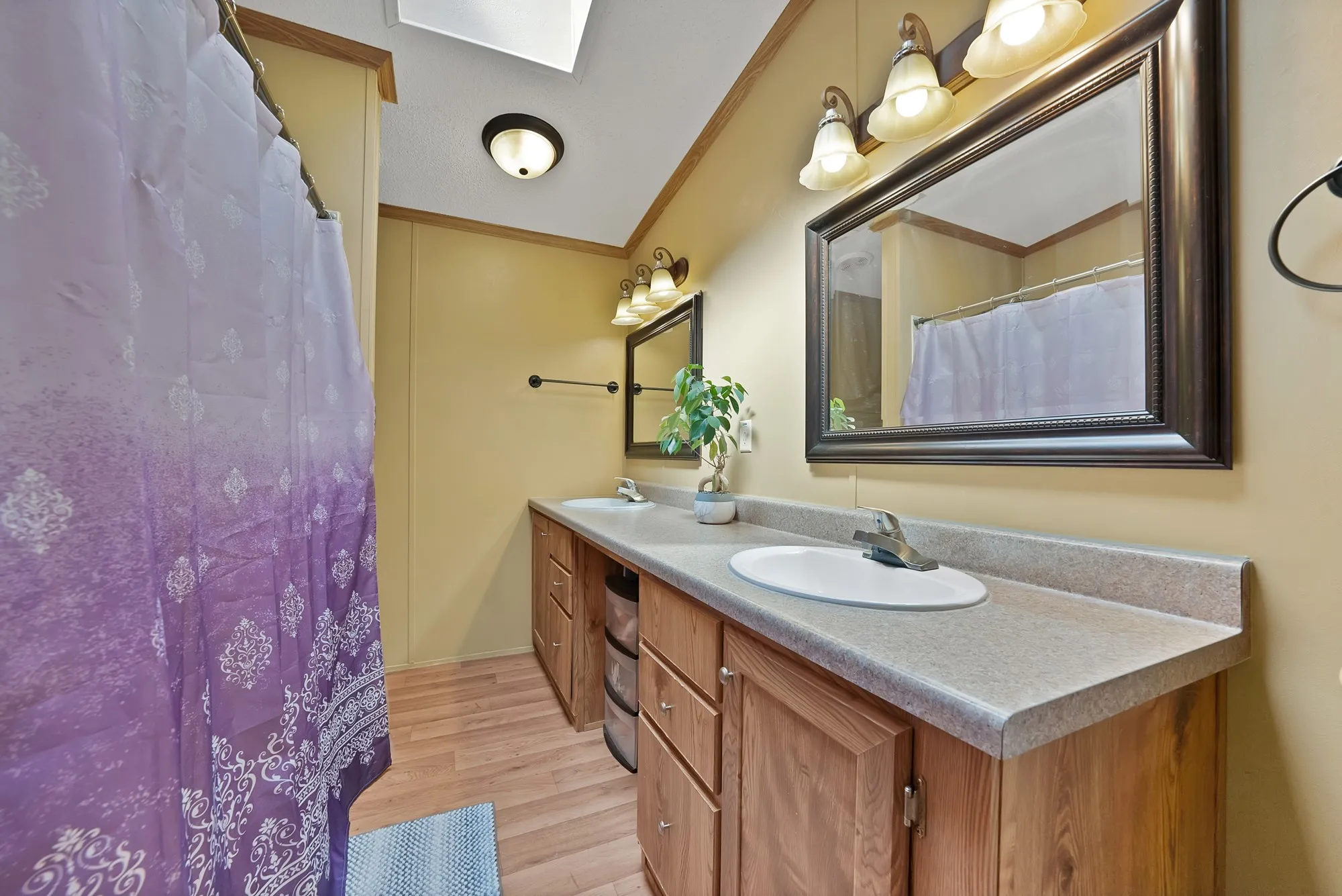 Dual vanity with integrated sinks, wood-finish cabinetry, and framed mirrors