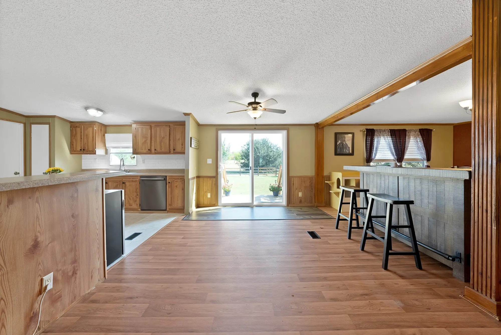 Open-concept living area with wood-finish flooring, a built-in bar, wood cabinetry, and sliding glass door to the exterior