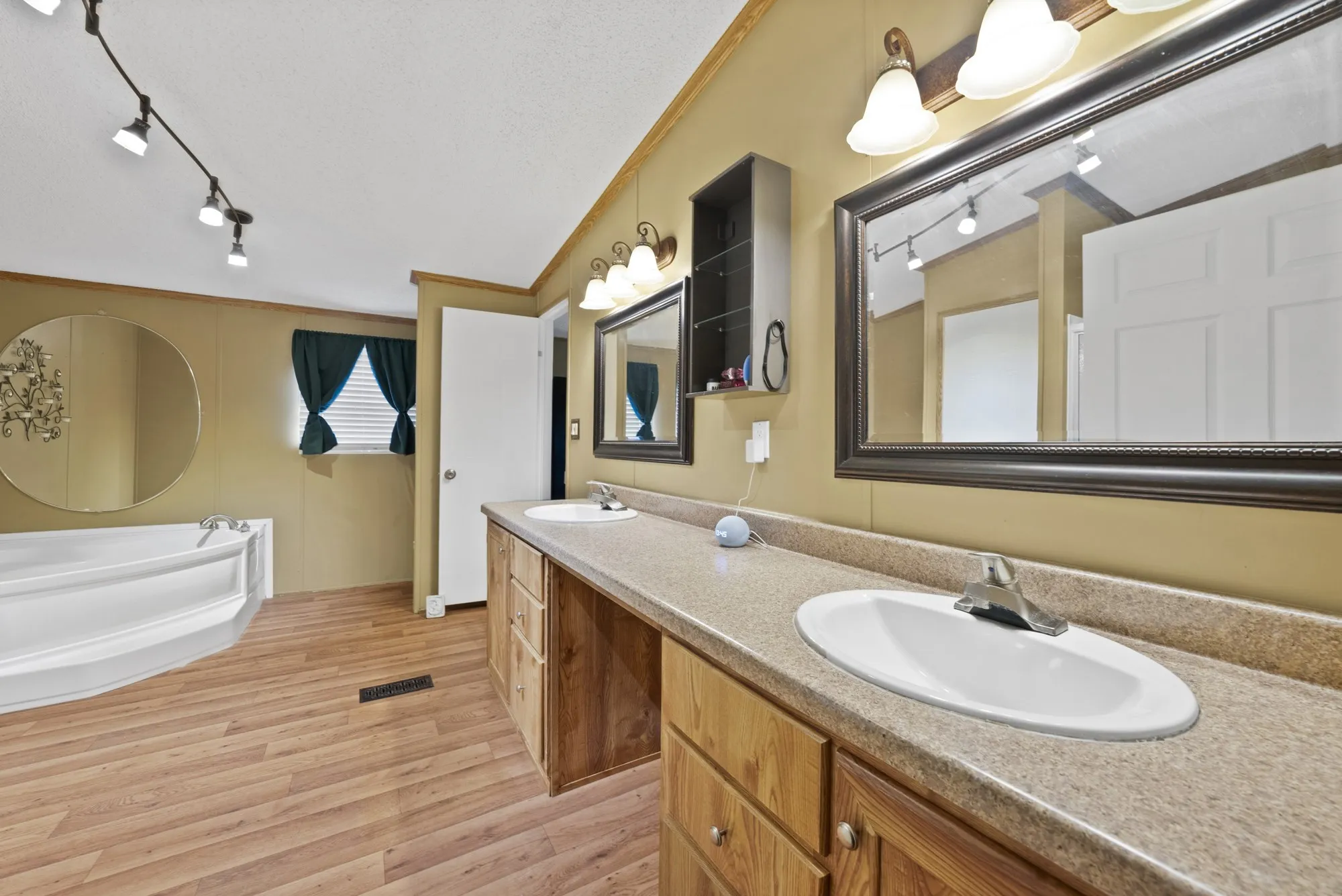 Dual vanity with integrated sinks, wood-finish cabinetry, and a large framed mirror