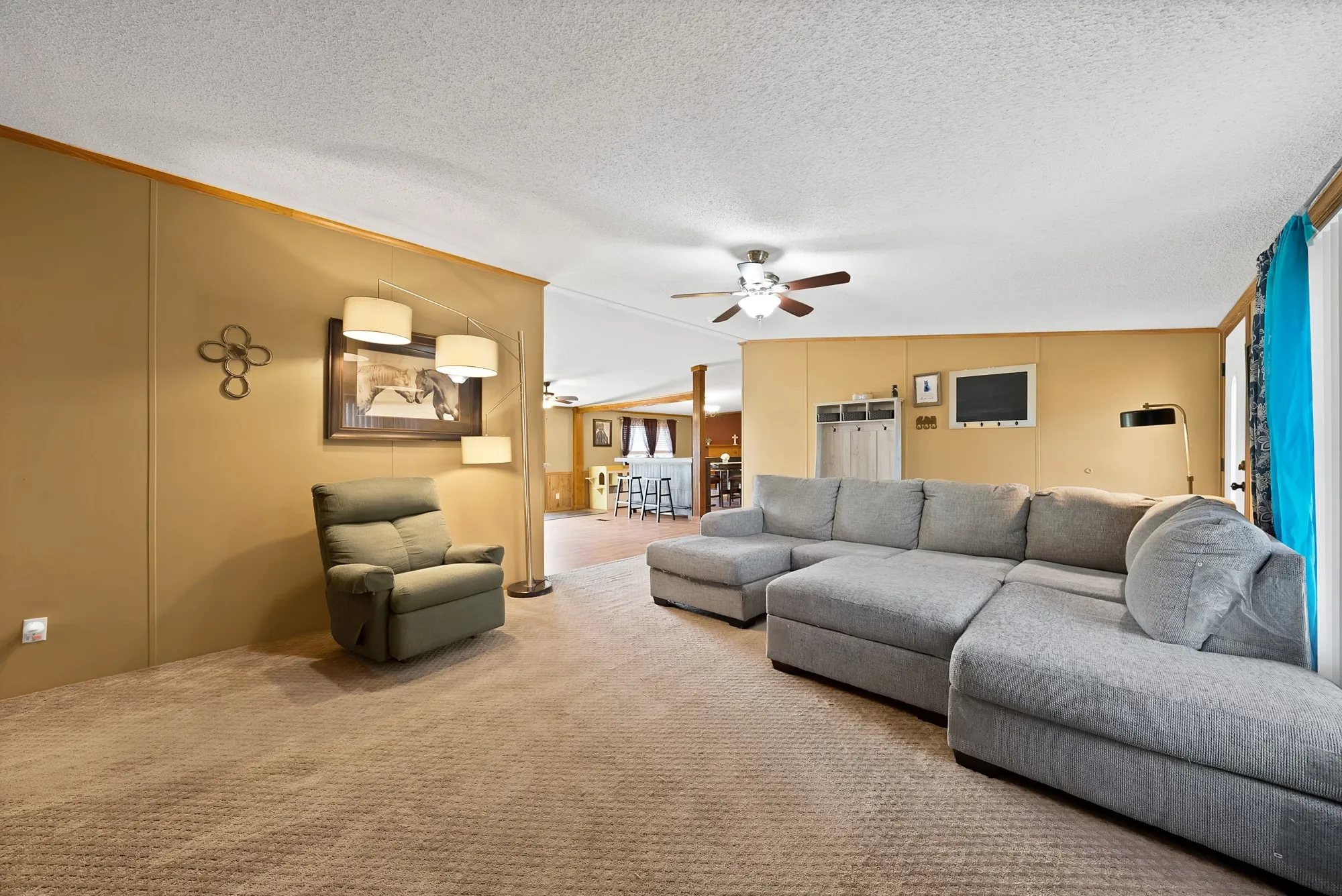 Carpeted living area with wood-trim walls and a ceiling fan
