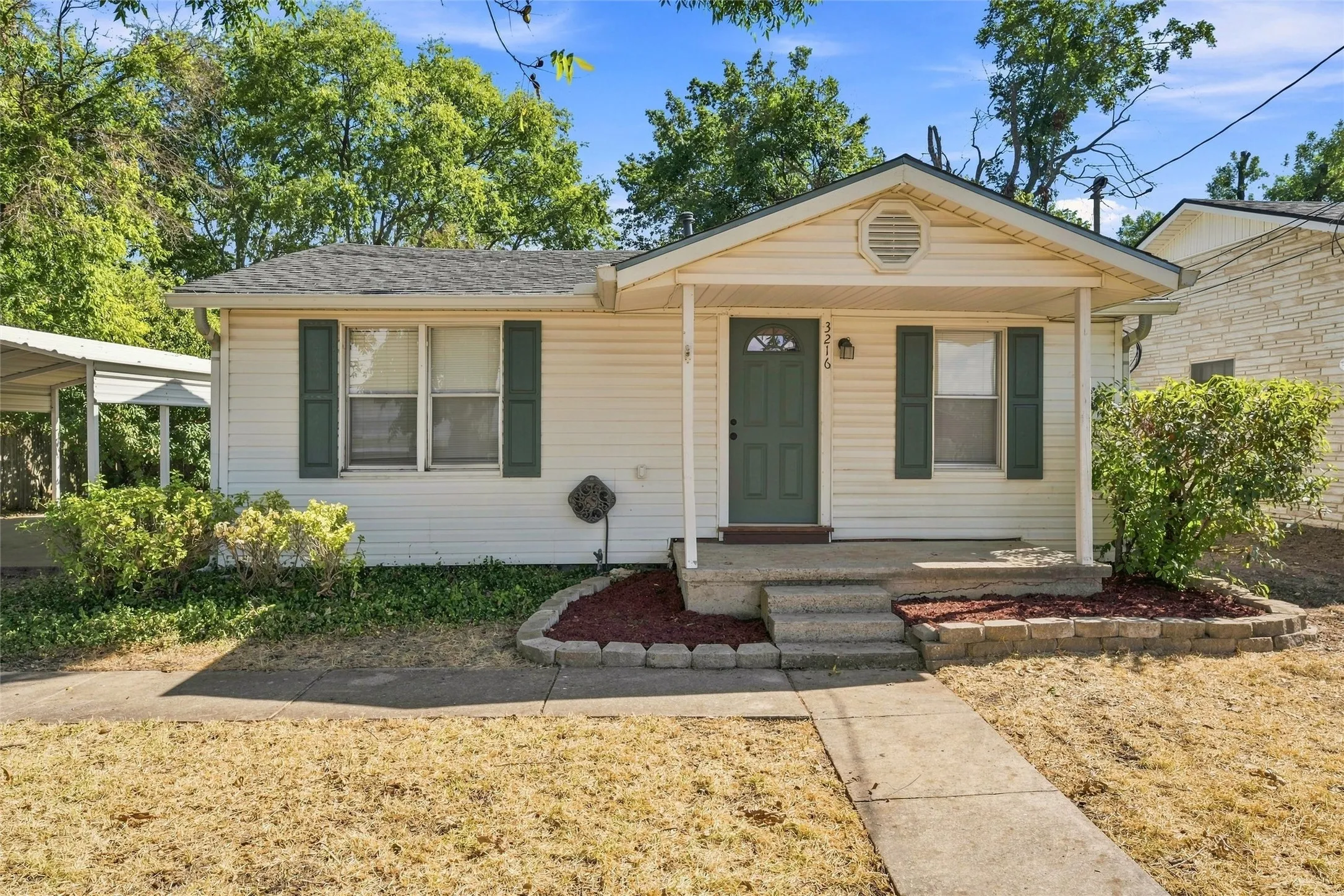 Front exterior featuring a covered porch, concrete steps, green shutters, and a walkway