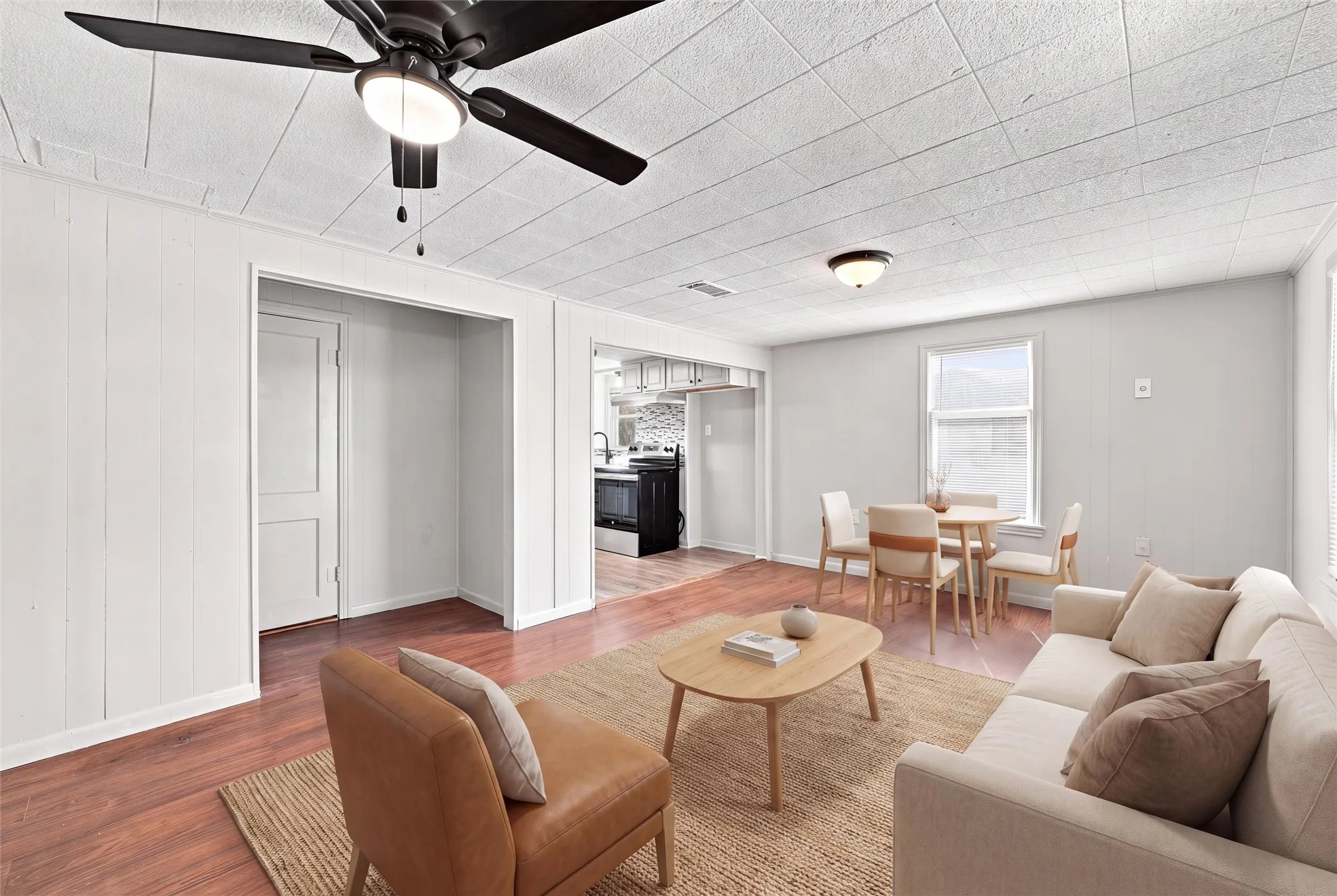 Open-concept living area featuring wood-finish flooring, a ceiling fan with integrated lighting, and recessed lighting