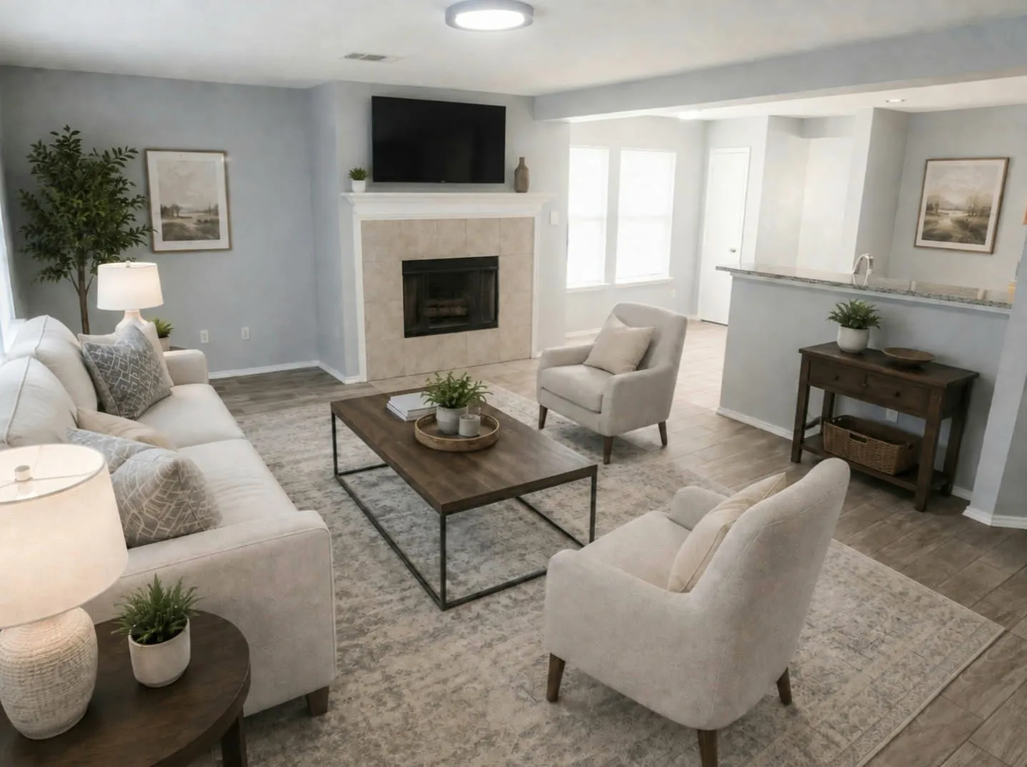 Living area featuring wood-like tile flooring, a built-in fireplace with a tiled surround, and bright lighting