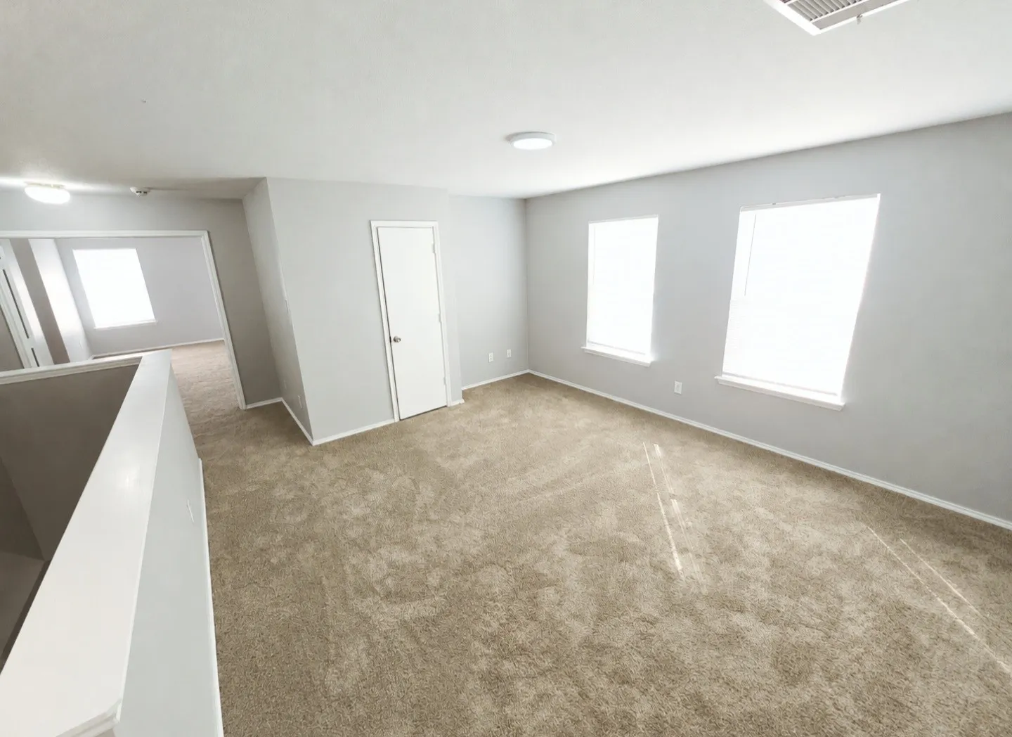 Spacious upstairs living space with new carpet and bright lighting.