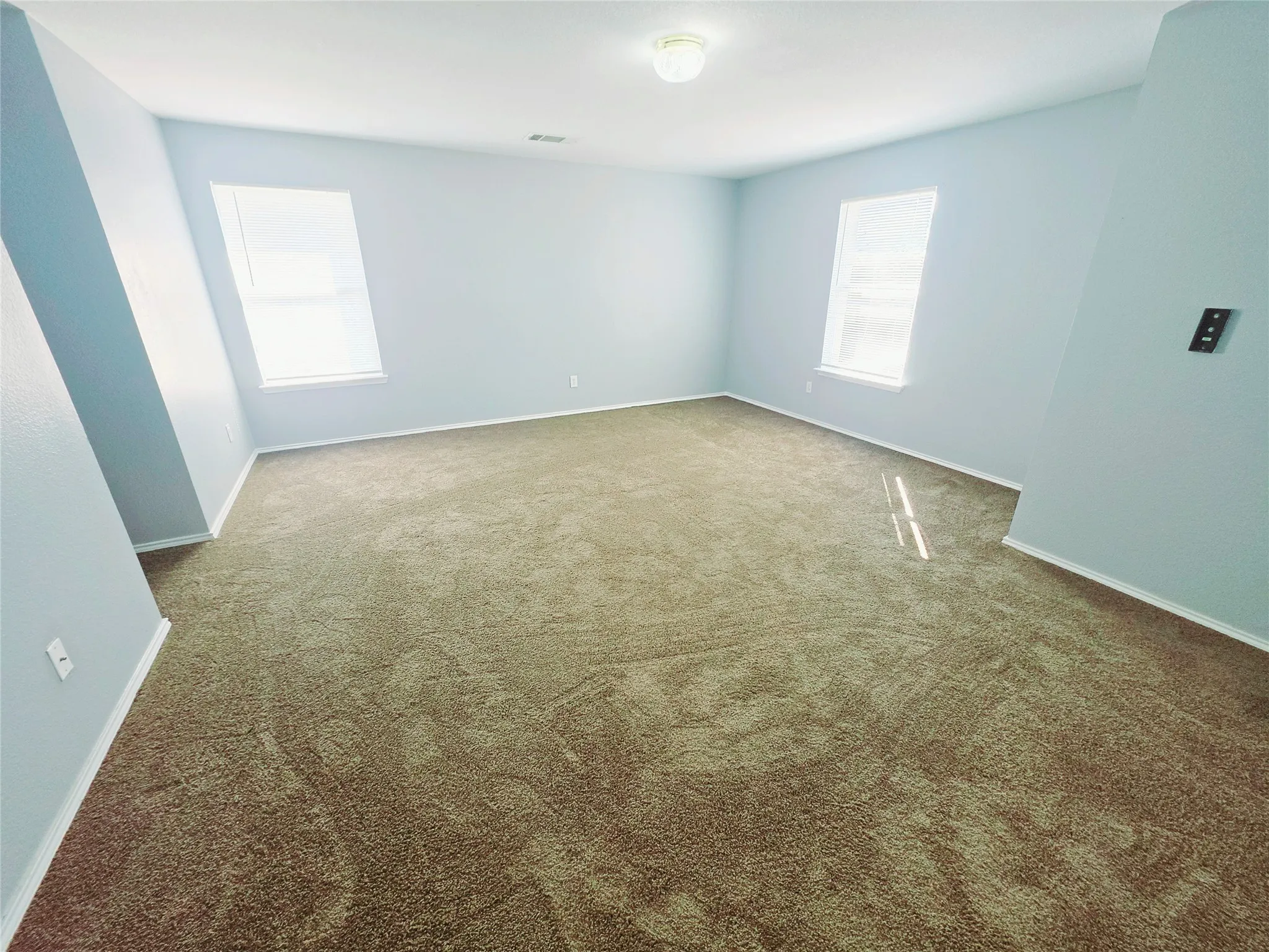 Spacious room with new carpet, multiple windows with blinds, walk-in closets.
