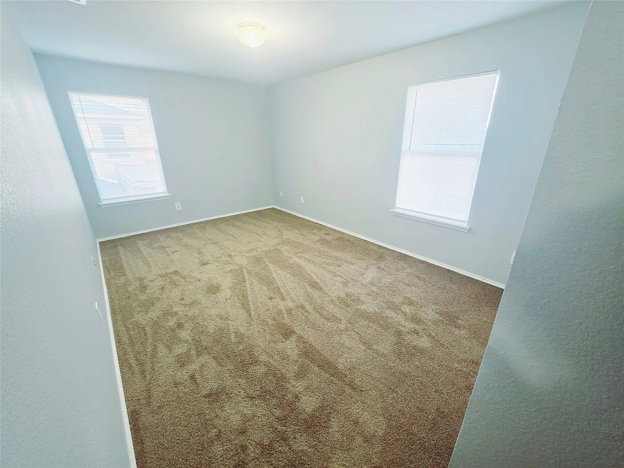 New carpet throughout, neutral wall color, and two windows with blinds