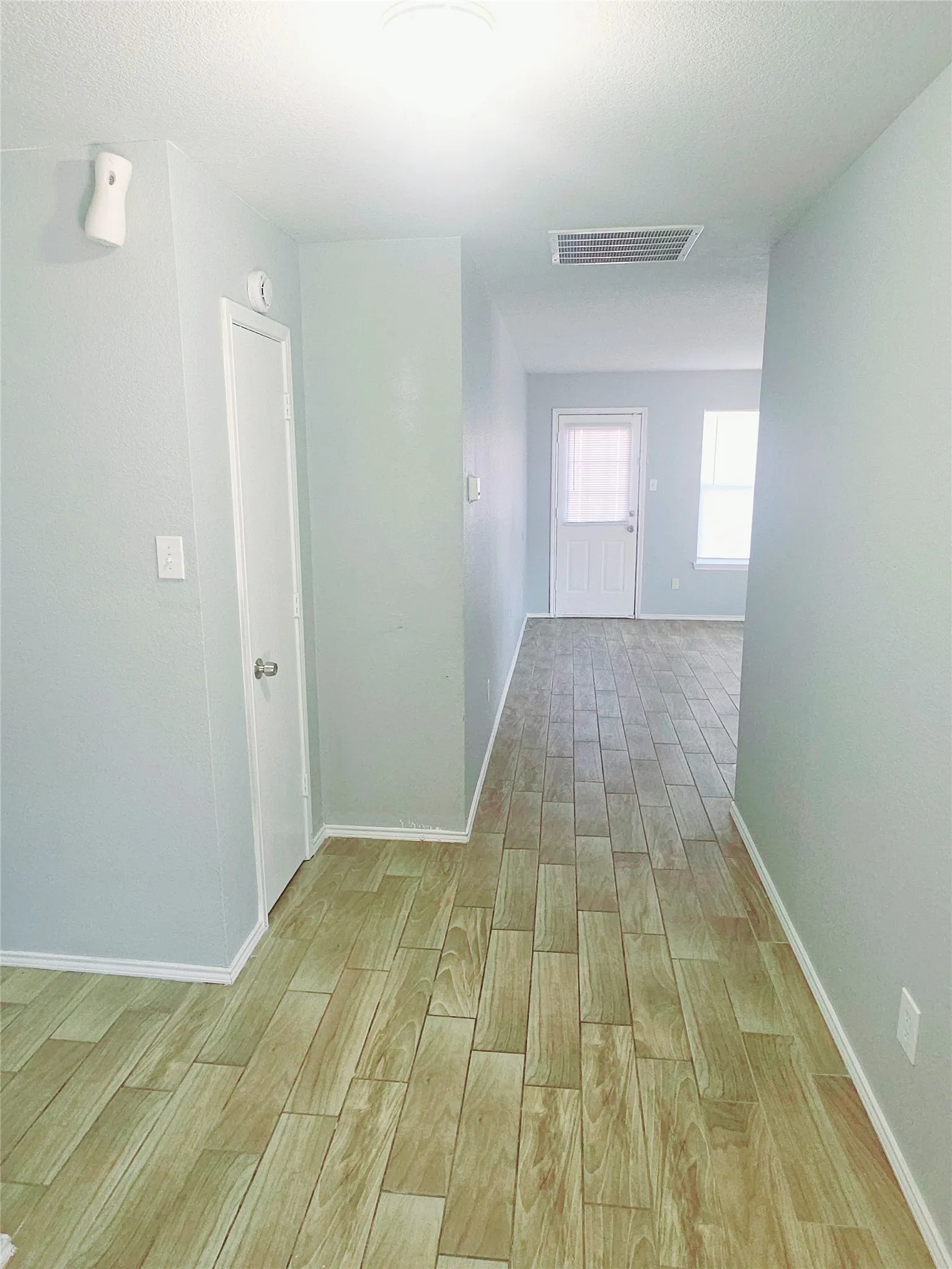 Wood-like tile flooring throughout, light-toned wall paint, and white trim