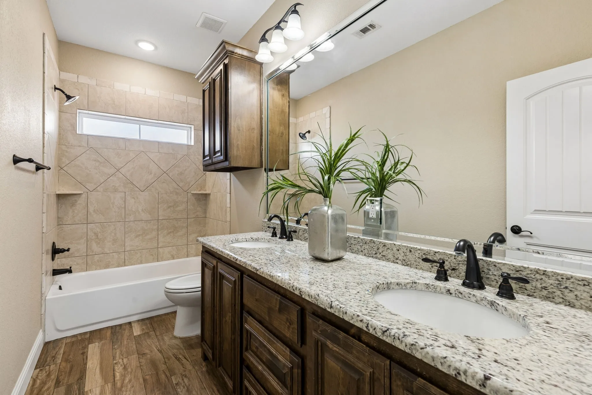 Dual vanity with stone-finish countertop, wood-finish cabinetry, and matte black fixtures