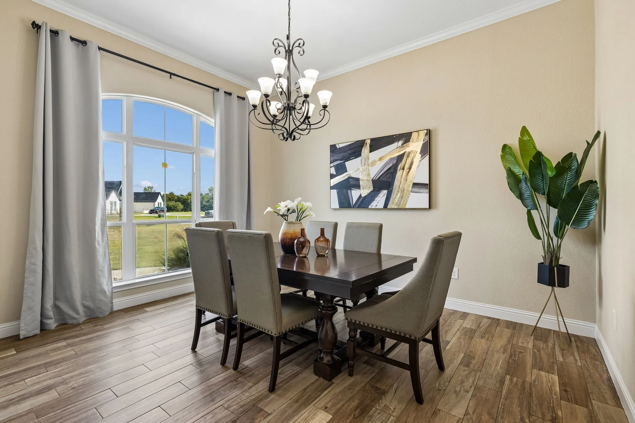 Arched window, crown molding, wood-finish flooring, and a chandelier