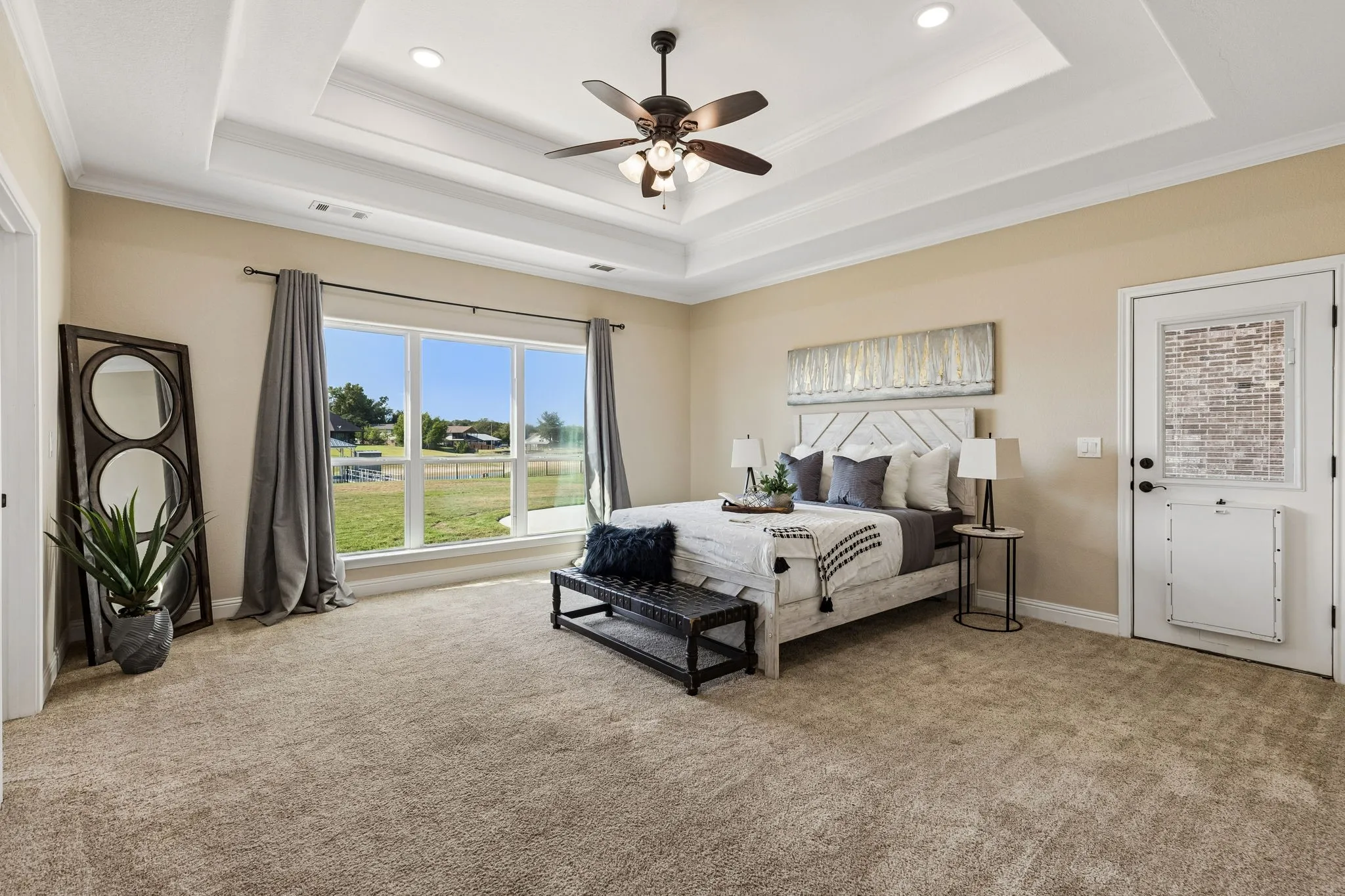 Tray ceiling with recessed lighting, ceiling fan, large window with expansive outdoor scenery, wall-to-wall carpeting, and an exterior door with integrated pet access