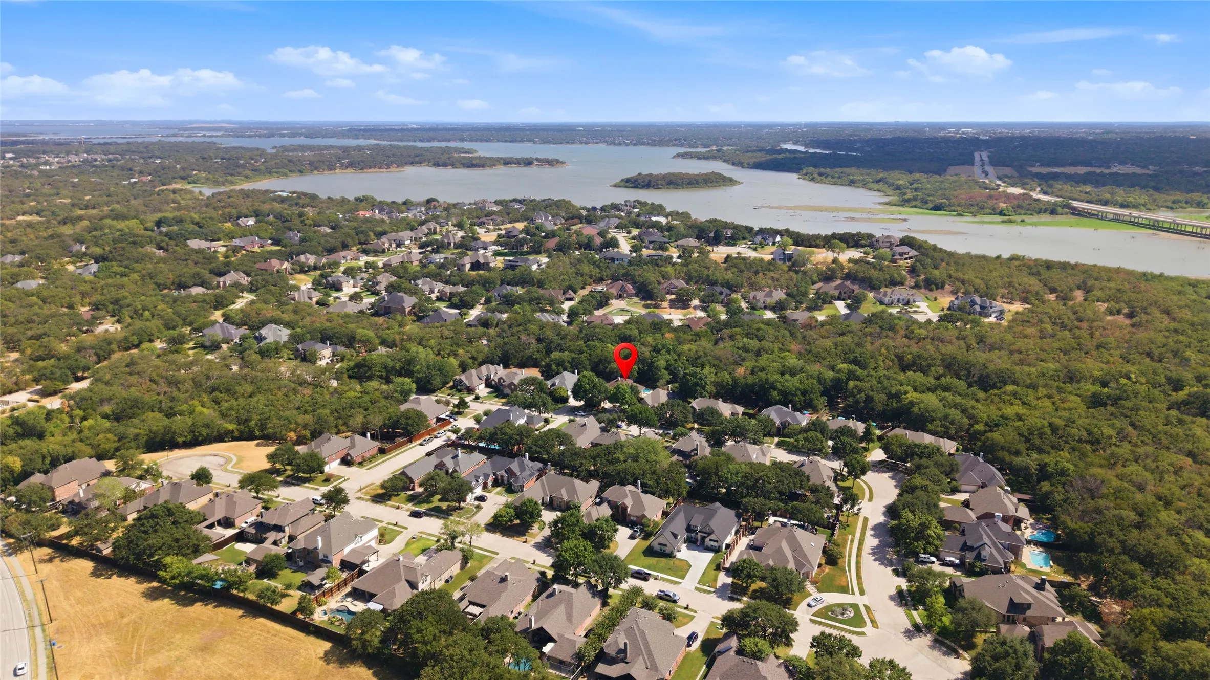 Aerial perspective showcasing a residential neighborhood with mature trees, adjacent to a large body of water