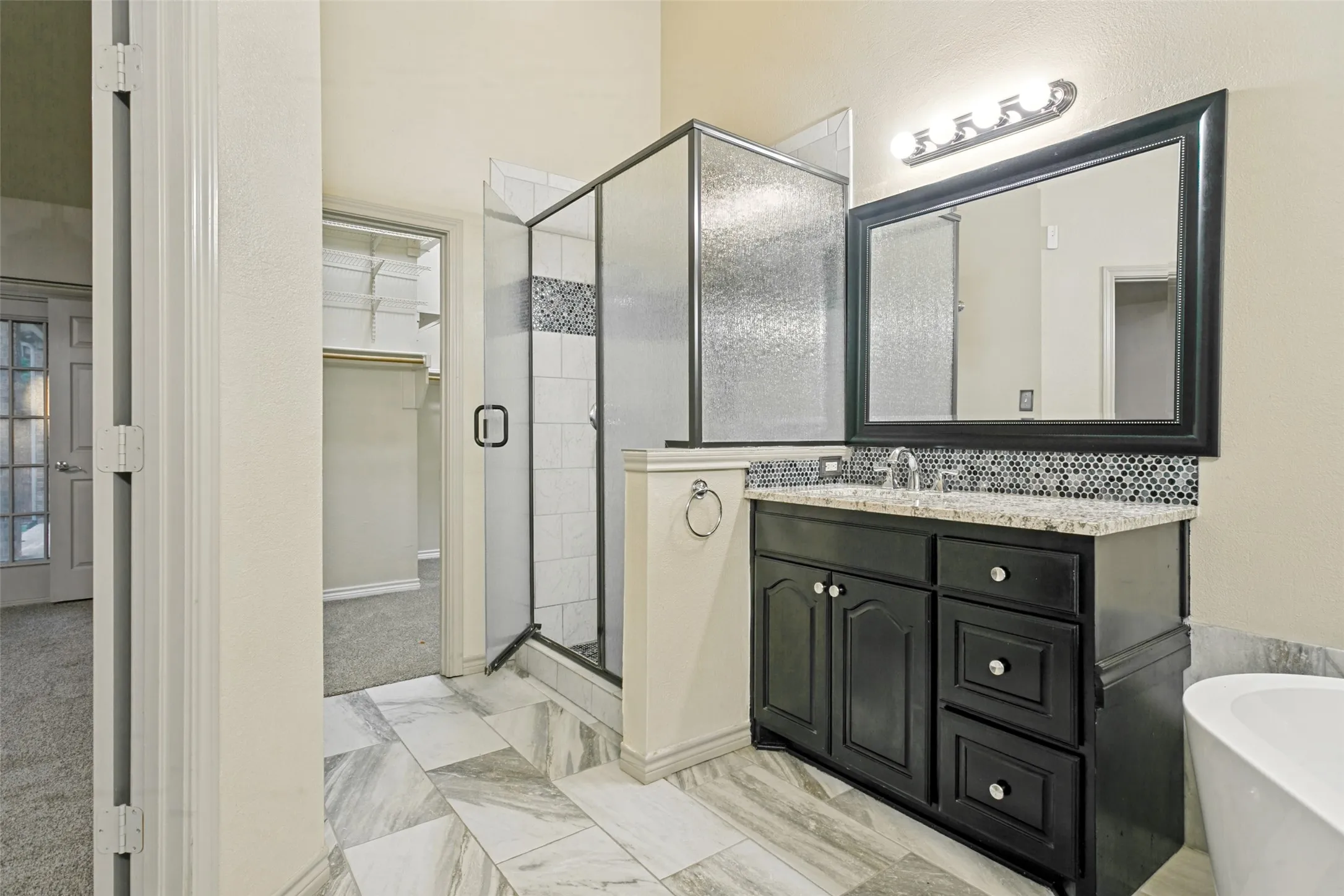 Single vanity with a light-toned countertop, mosaic tile backsplash, and dark wood cabinetry