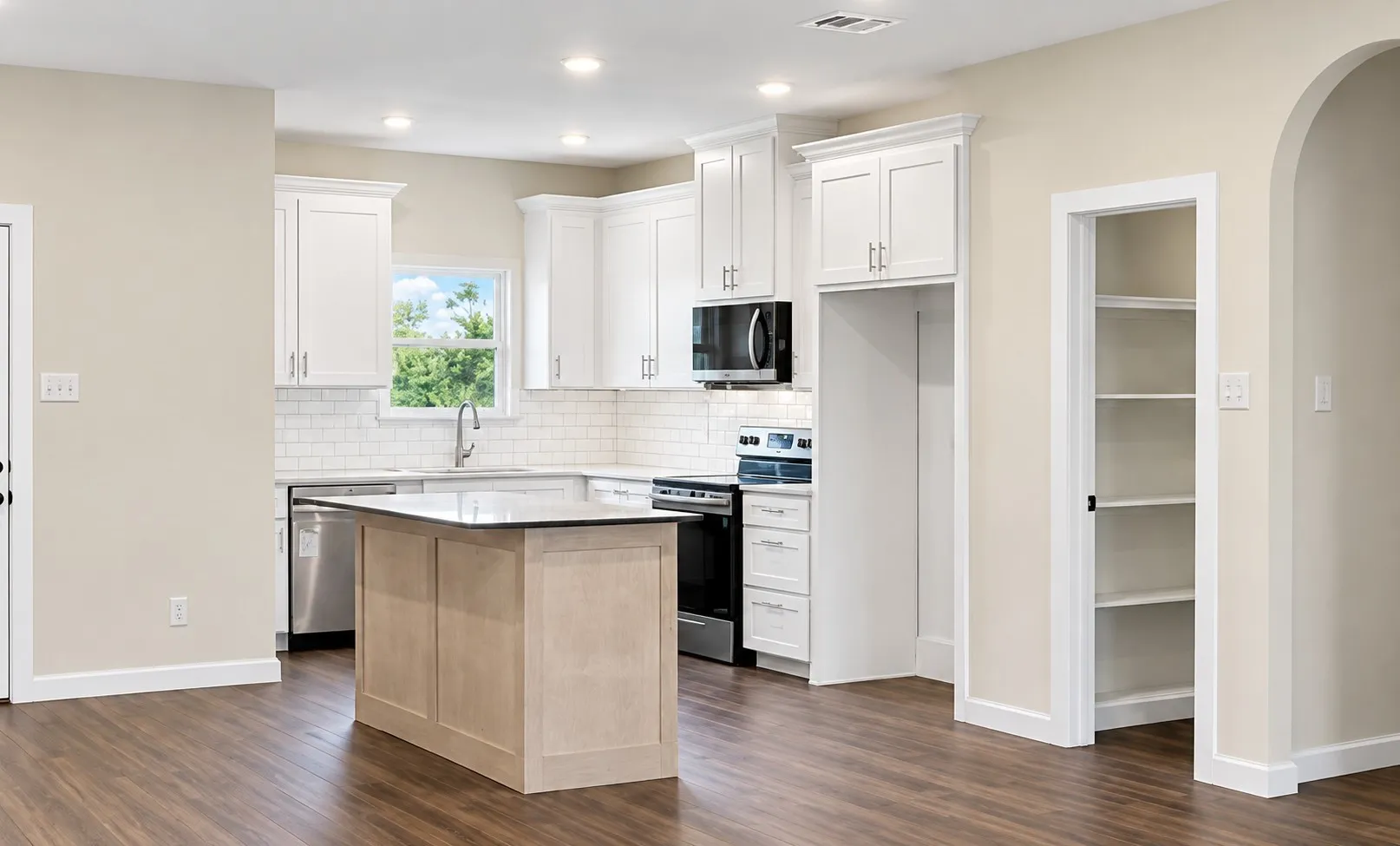 Kitchen featuring white shaker cabinetry, stainless steel appliances, a center island with countertop, and wood-finish flooring