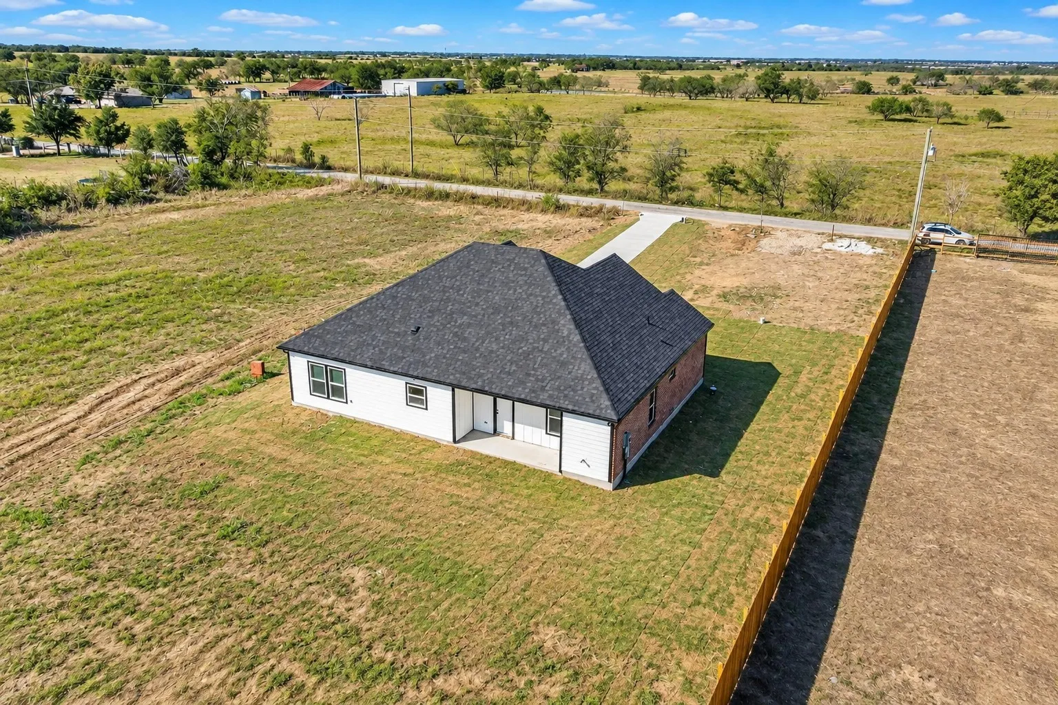New construction residence featuring a dark shingle roof, white siding, and brick accents