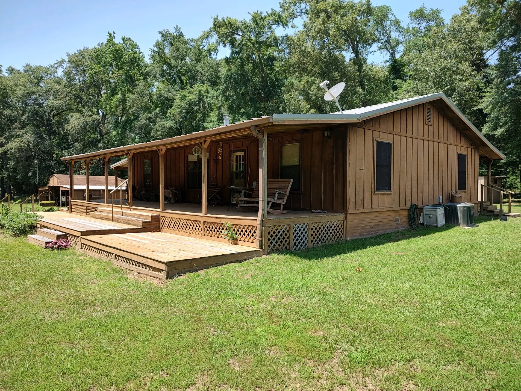 Front view of property with covered porch, and deck, 3-car carport in background.