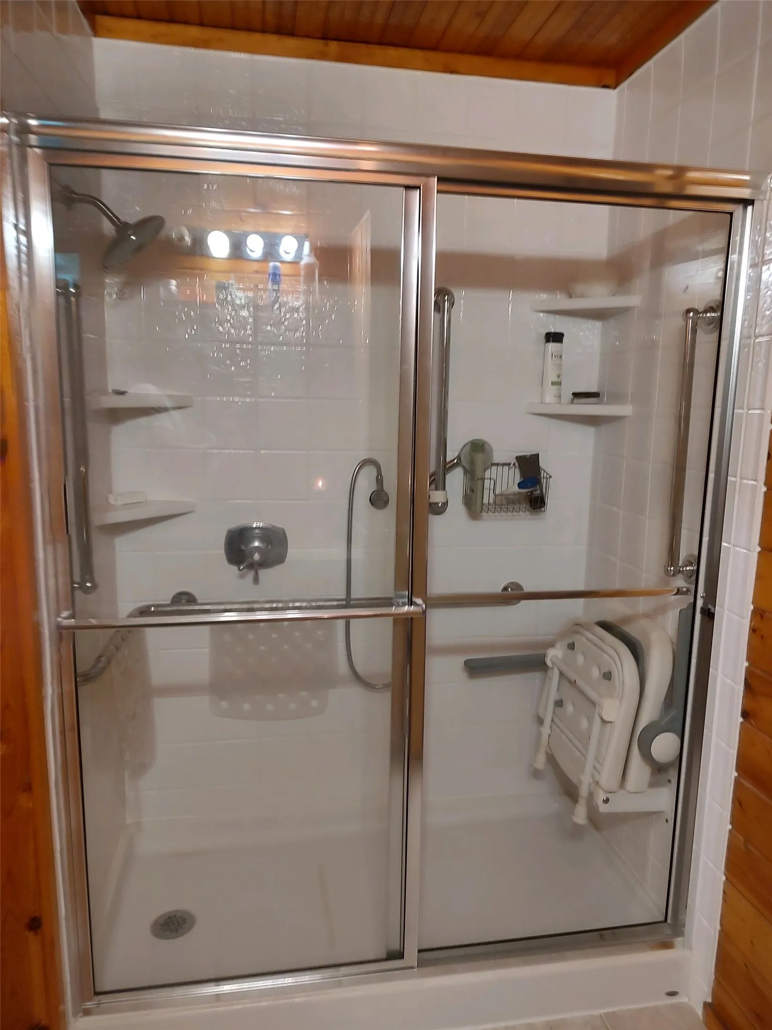 Primary bathroom. Shower features fold-down shower seat, shower head, shower wand, and handrails.