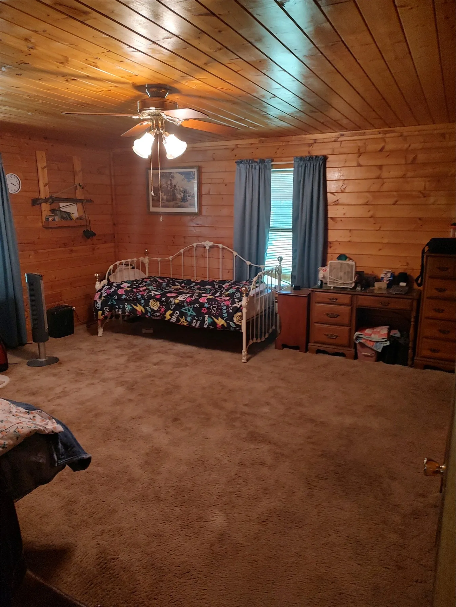Primary bedroom with wood walls and ceiling, carpet.