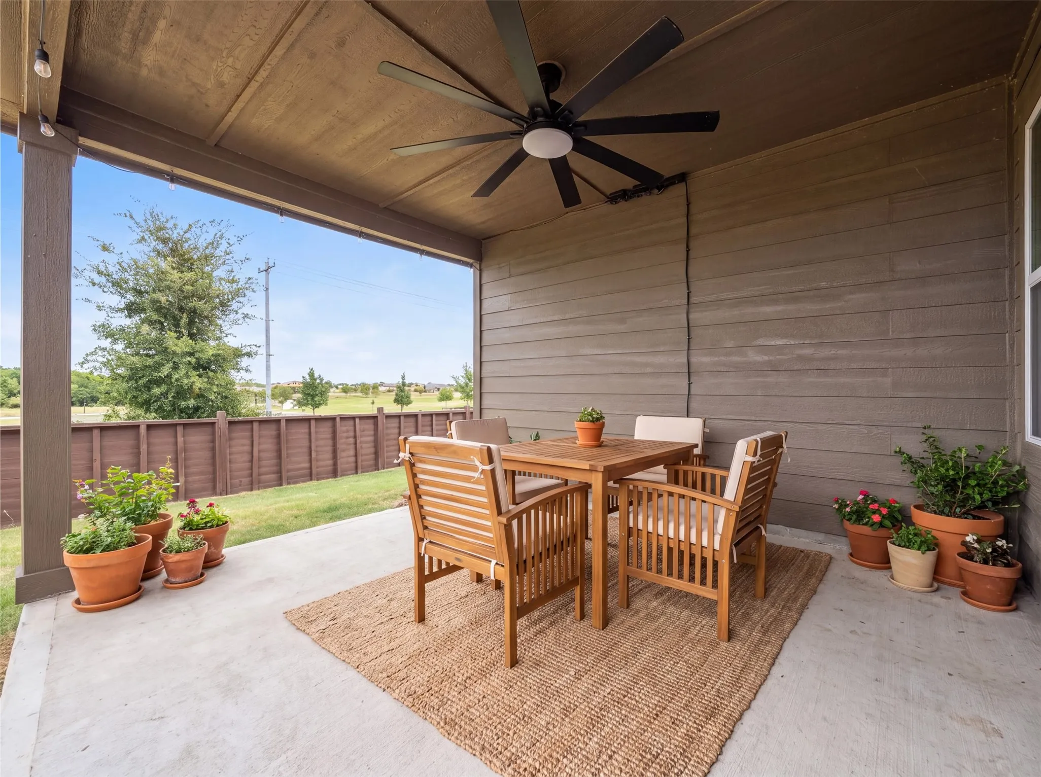 Covered patio with a ceiling fan, concrete flooring, and a fenced perimeter