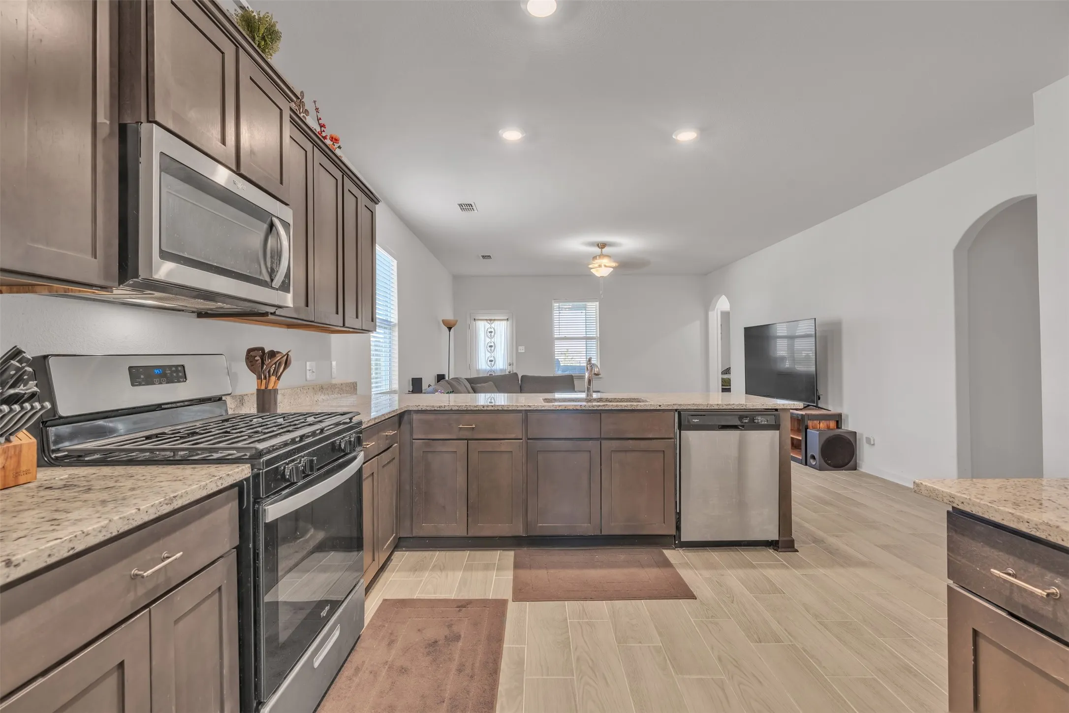 Spacious kitchen featuring wood-finish cabinetry, stainless steel appliances including a dual-oven range, granite countertops, and a large center island