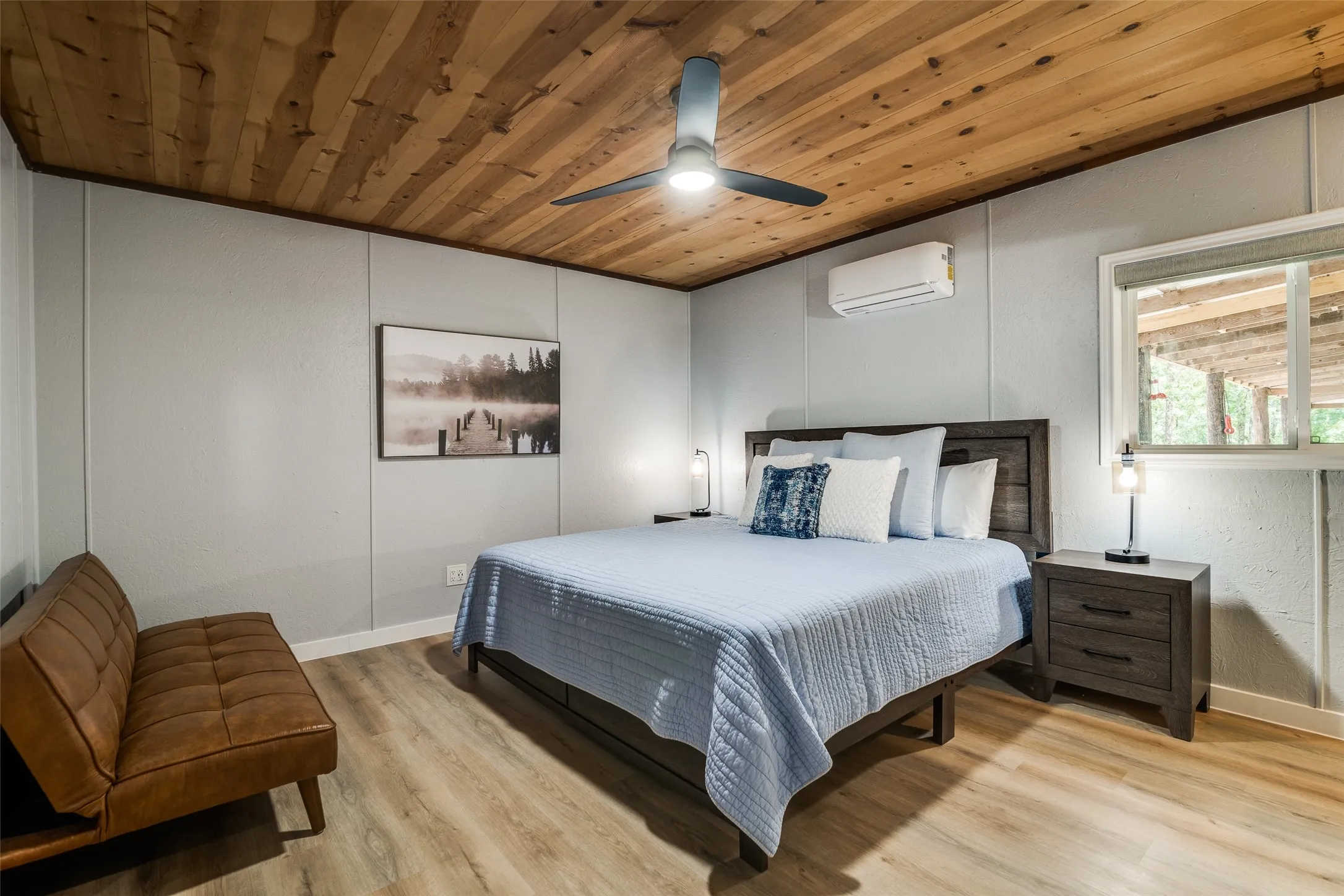 Wood-paneled ceiling with a central ceiling fan, light gray paneled walls, and wood-finish flooring