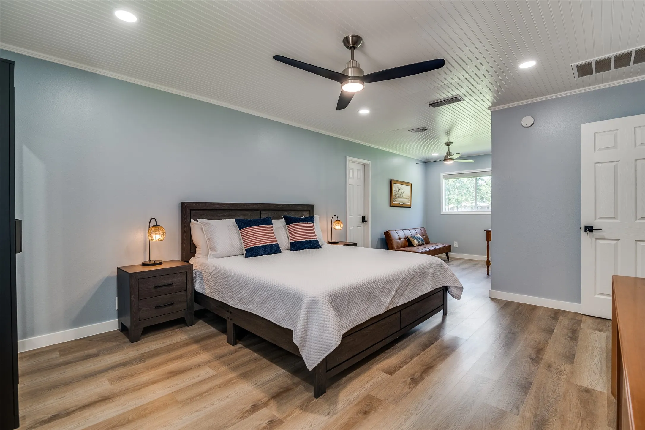 Light blue walls with wood-finish flooring, white paneled doors, and a beadboard ceiling