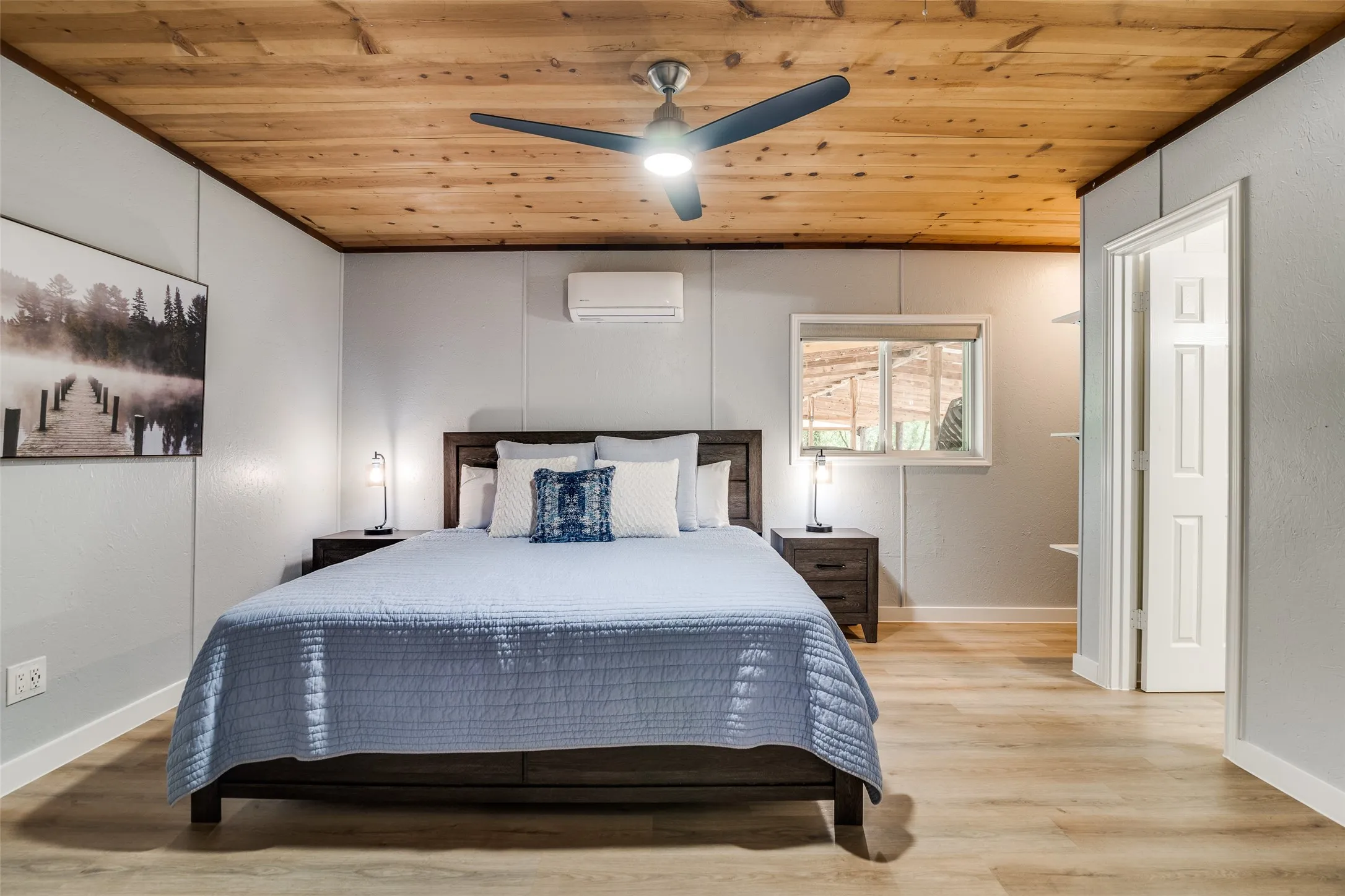 Wood-plank ceiling with a ceiling fan, wall-mounted climate control unit, and wood-finish flooring