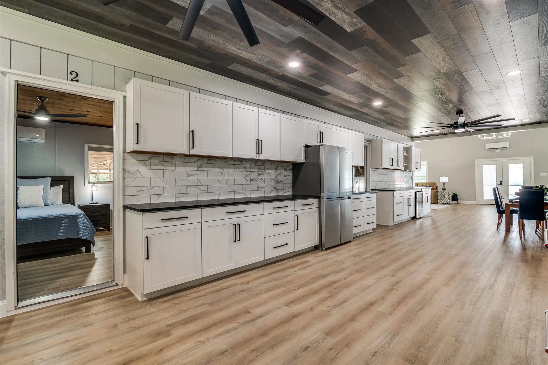 Full kitchen with white cabinetry, black countertops, and a subway tile backsplash