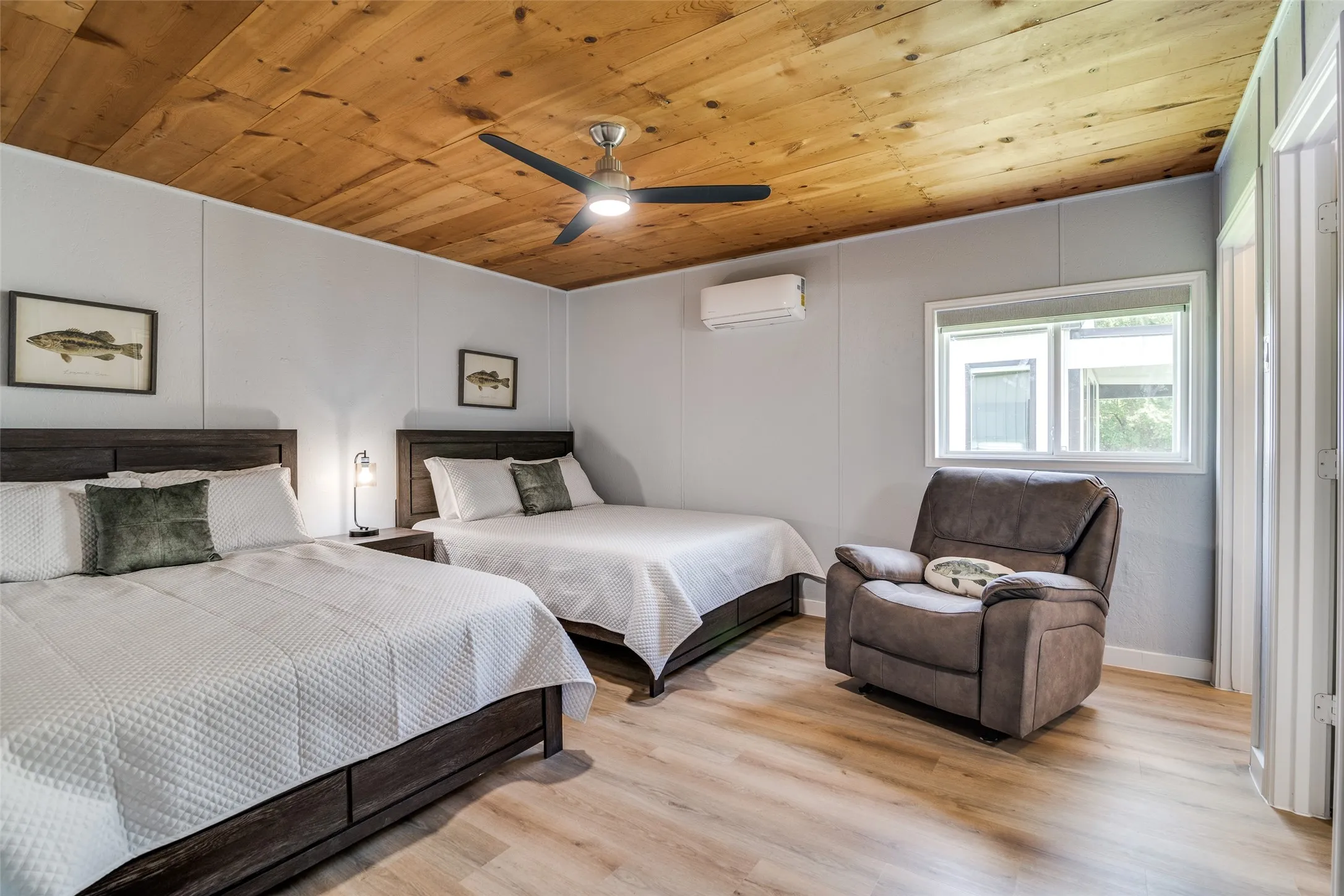 Wood-finish ceiling, ceiling fan with integrated lighting, wall-mounted air conditioning unit, and wood-finish flooring