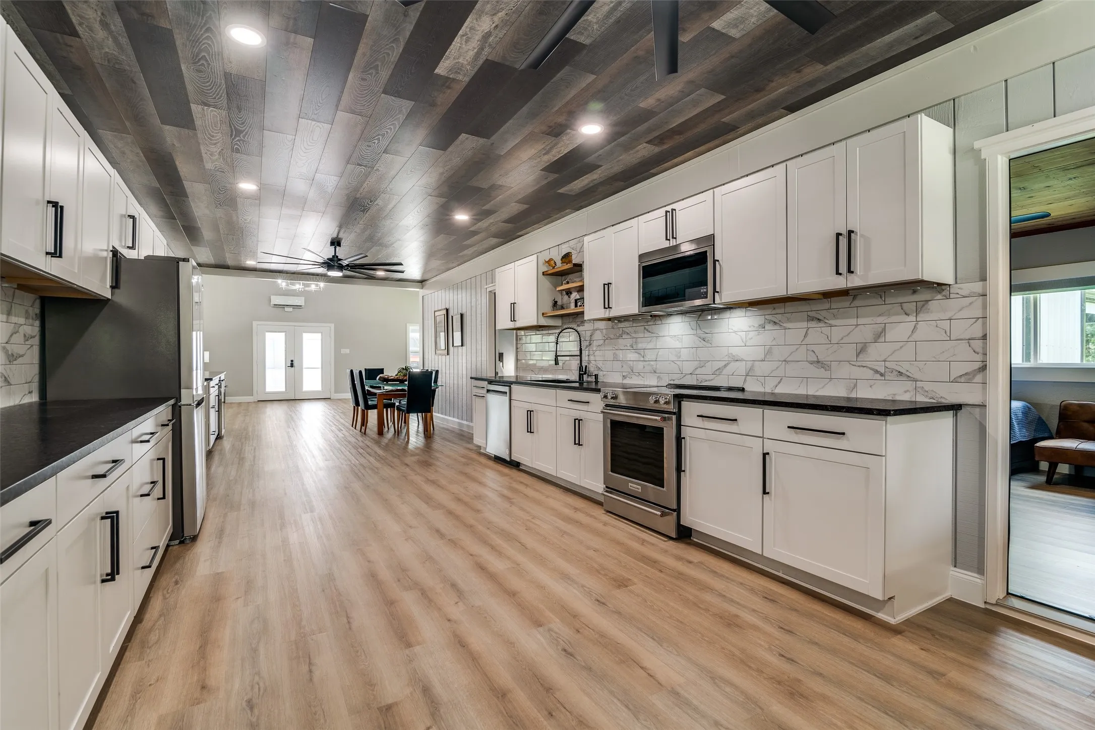 Kitchen featuring light wood-finish flooring, white cabinetry, dark countertops, and stainless steel appliances