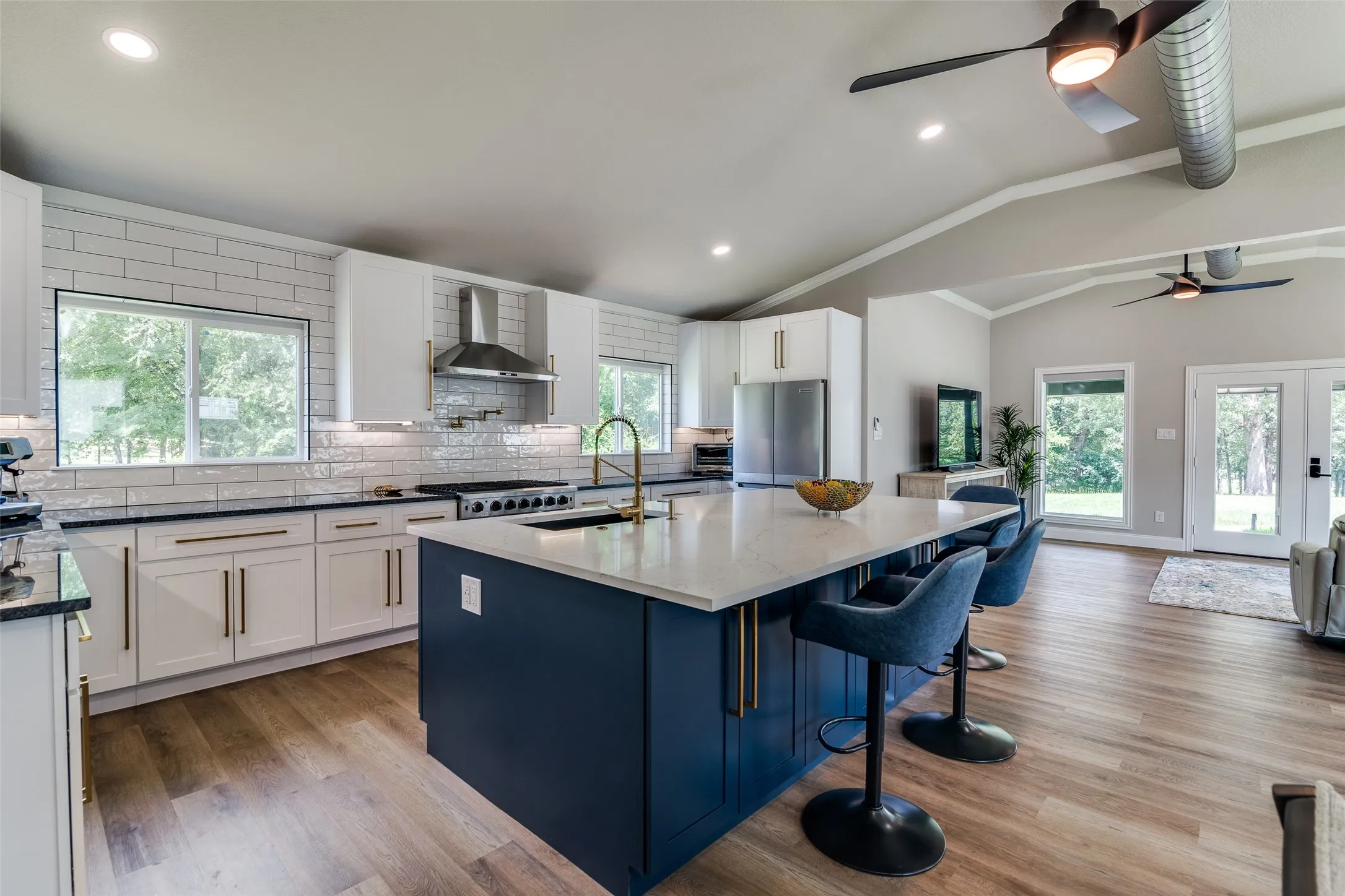 Kitchen featuring a large island with seating, white shaker cabinetry, subway tile backsplash, and wood-finish flooring
