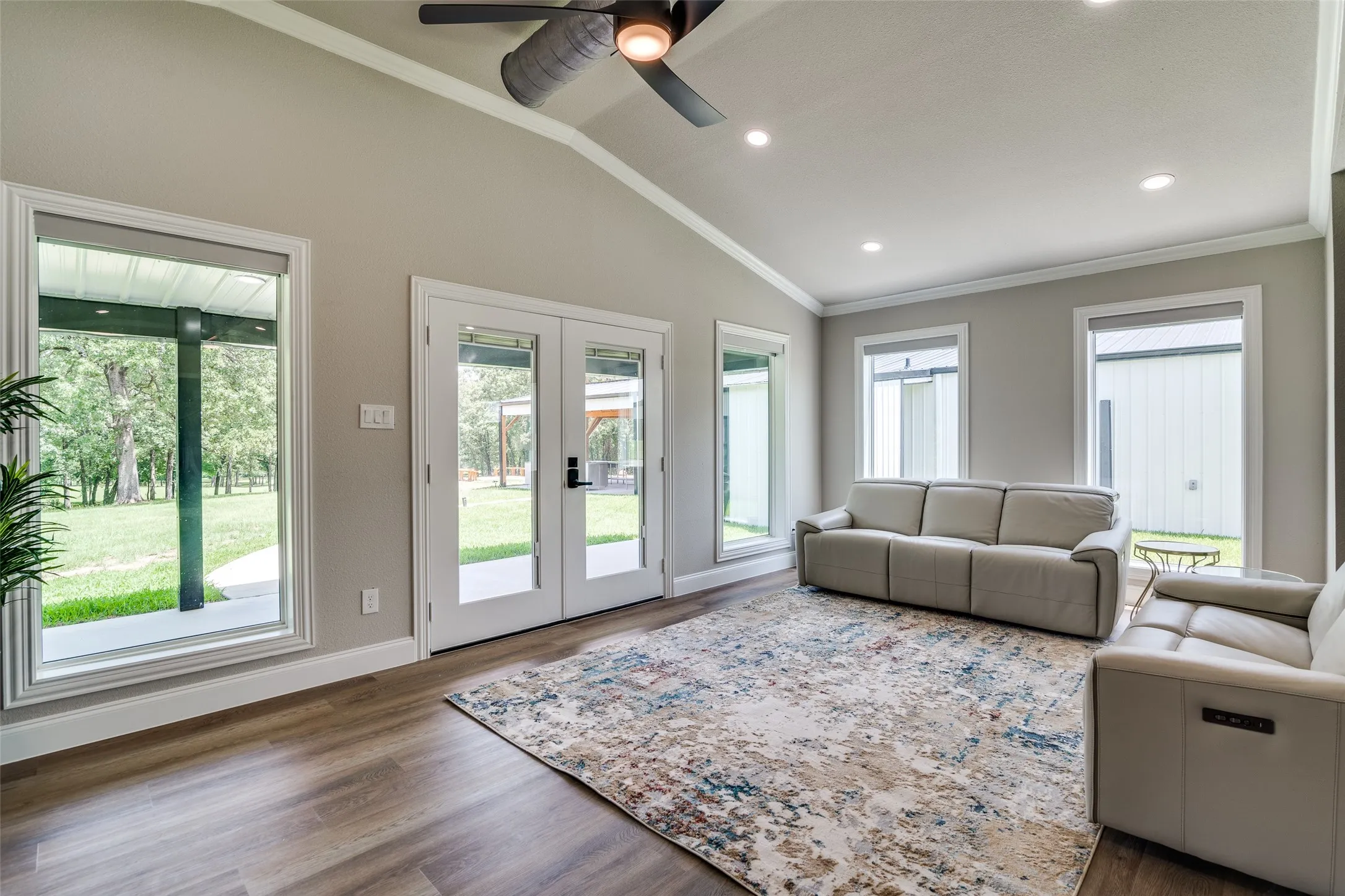 Vaulted ceilings, recessed lighting, wood-finish flooring, white trim, and a ceiling fan