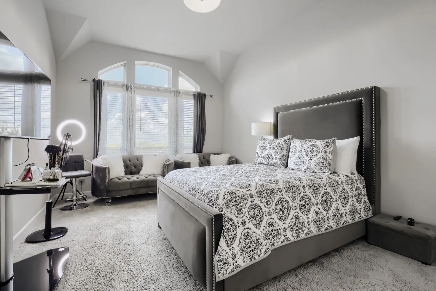 Room featuring an arched window, soft gray carpeting, and light-toned walls