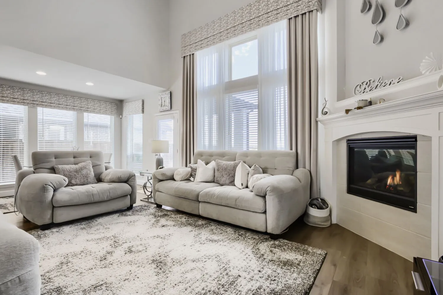 Living area featuring a gas fireplace, wood-finish flooring, vaulted ceilings, and extensive window treatments