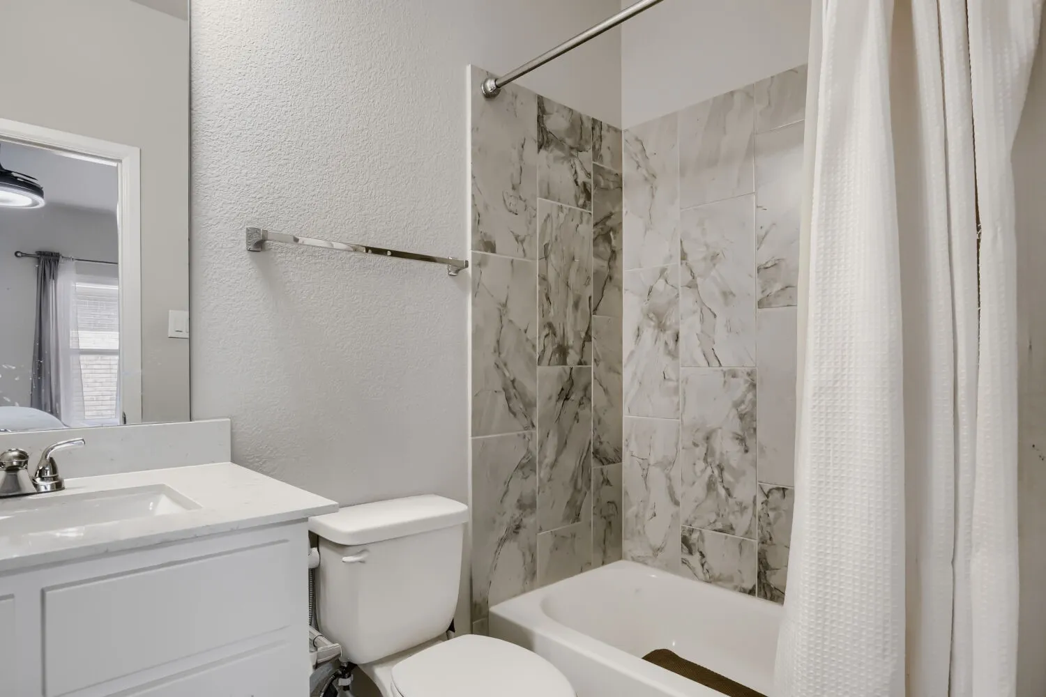 White vanity with an integrated sink, polished chrome faucet, and a tiled shower surround