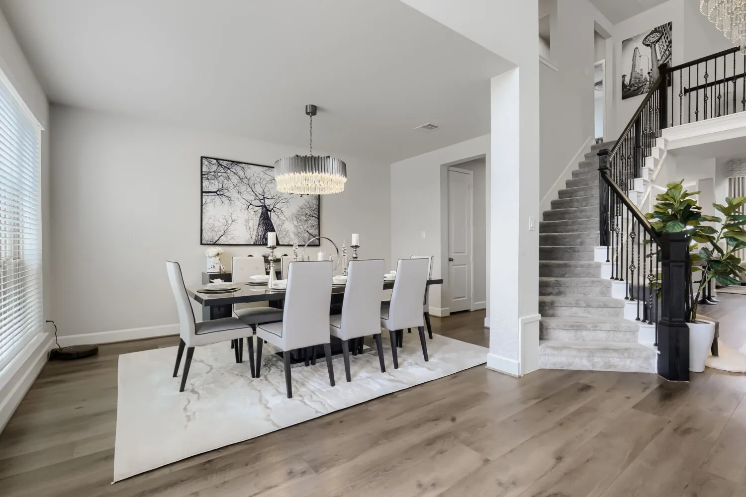 Wood-finish flooring throughout, with a carpeted staircase featuring a wrought iron and wood baluster system