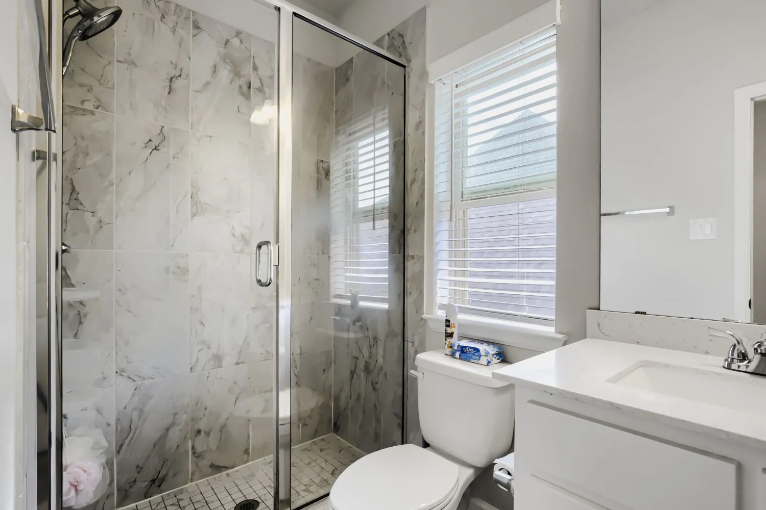 Glass-enclosed shower with marble-finish tile surround and a tiled floor