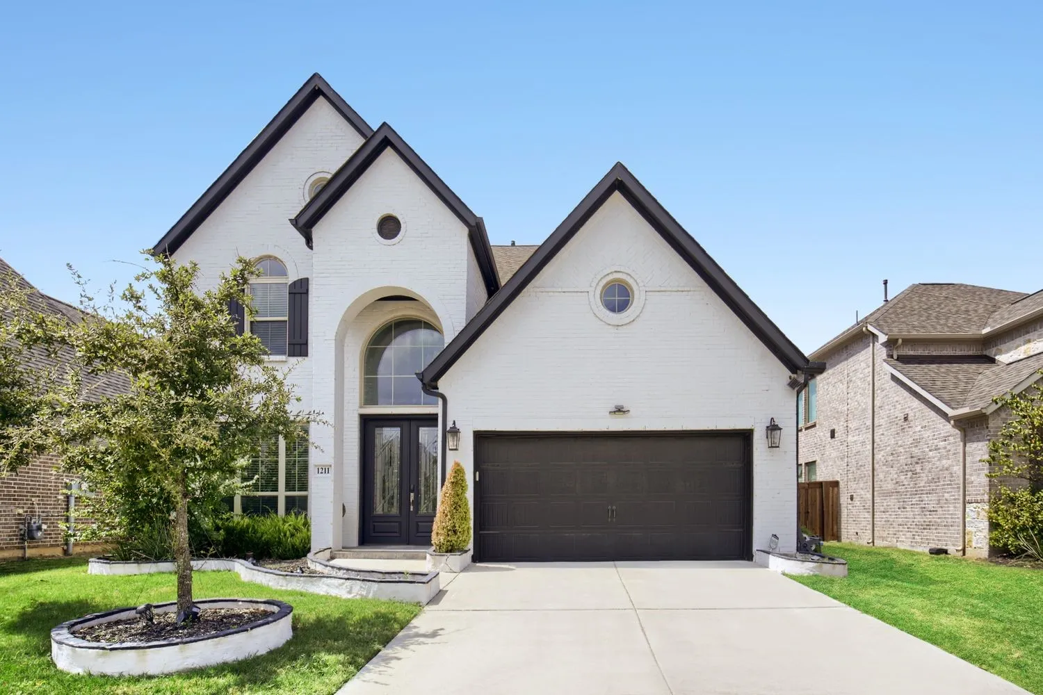 White brick exterior with dark trim accents and a prominent arched entry