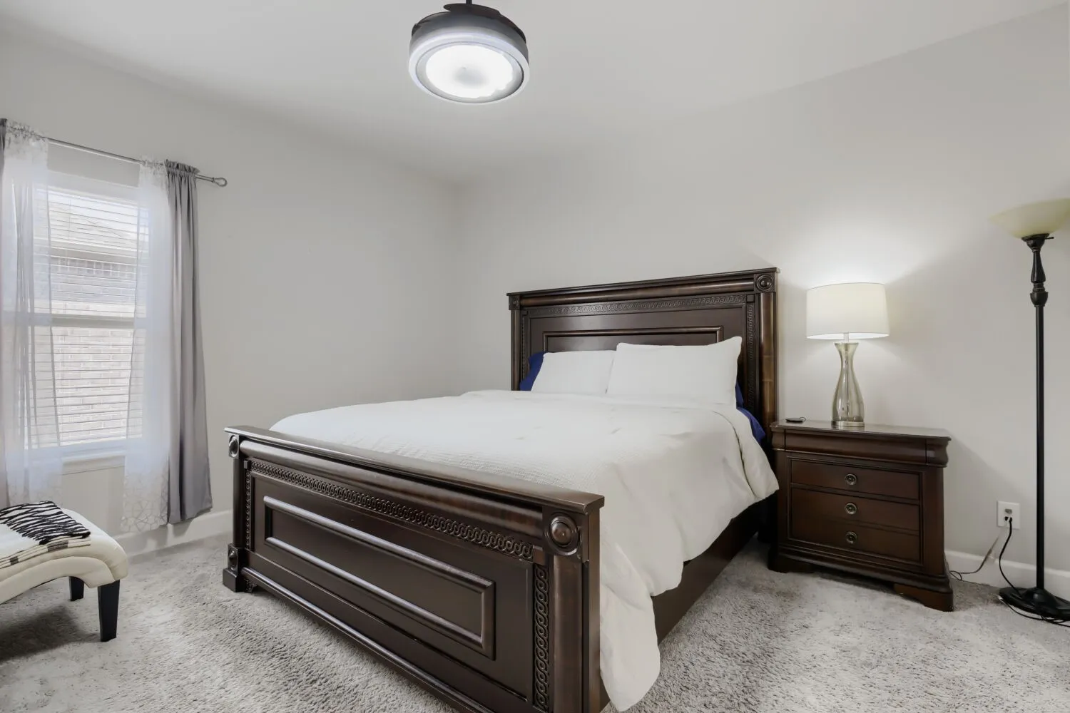 Wall-to-wall carpeting with window blinds and sheer curtains
