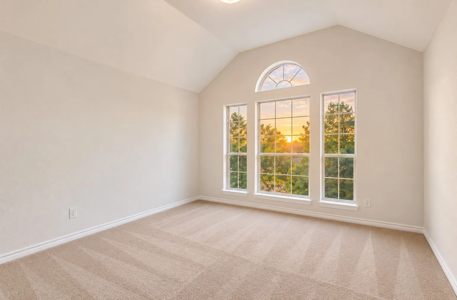 Vaulted ceiling with a half-round window, three large windows, and neutral carpeting