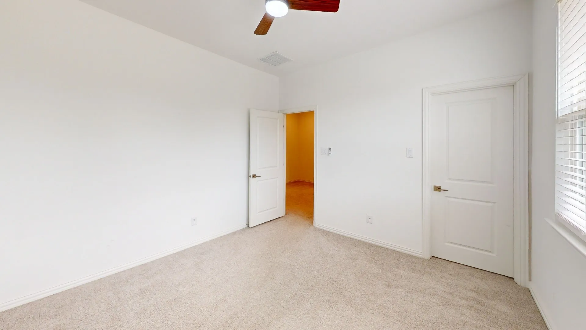 Carpeted flooring, white walls, two-panel interior doors, and a ceiling fan