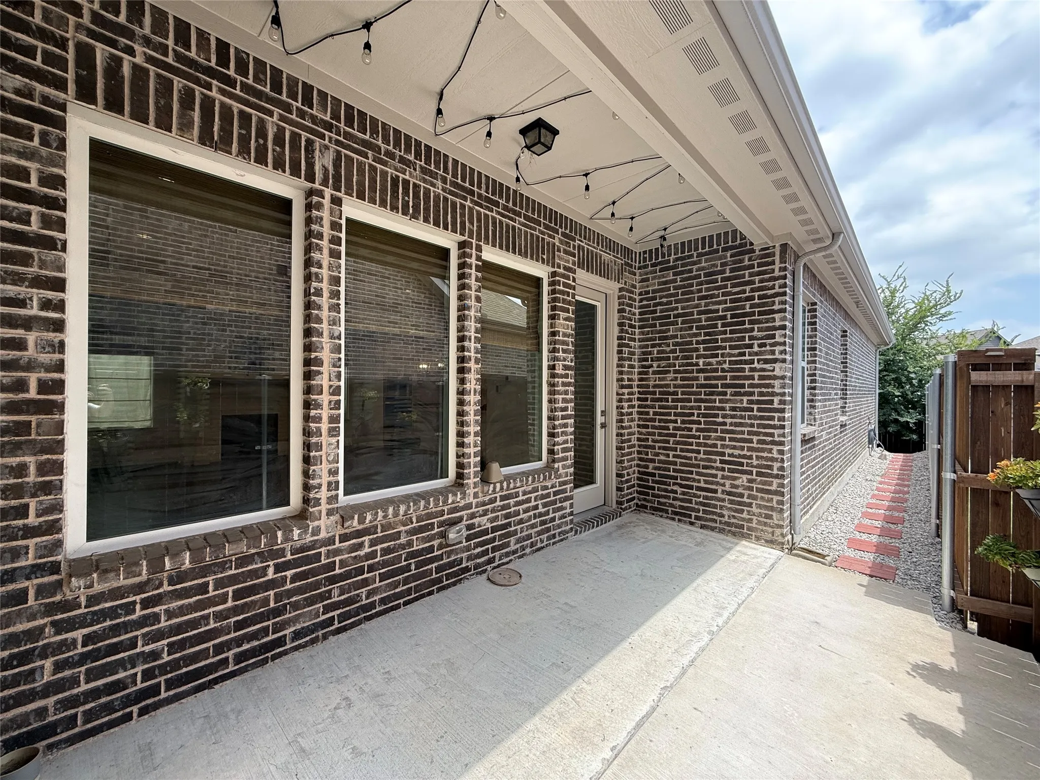 Brick exterior with white window trim and a concrete patio