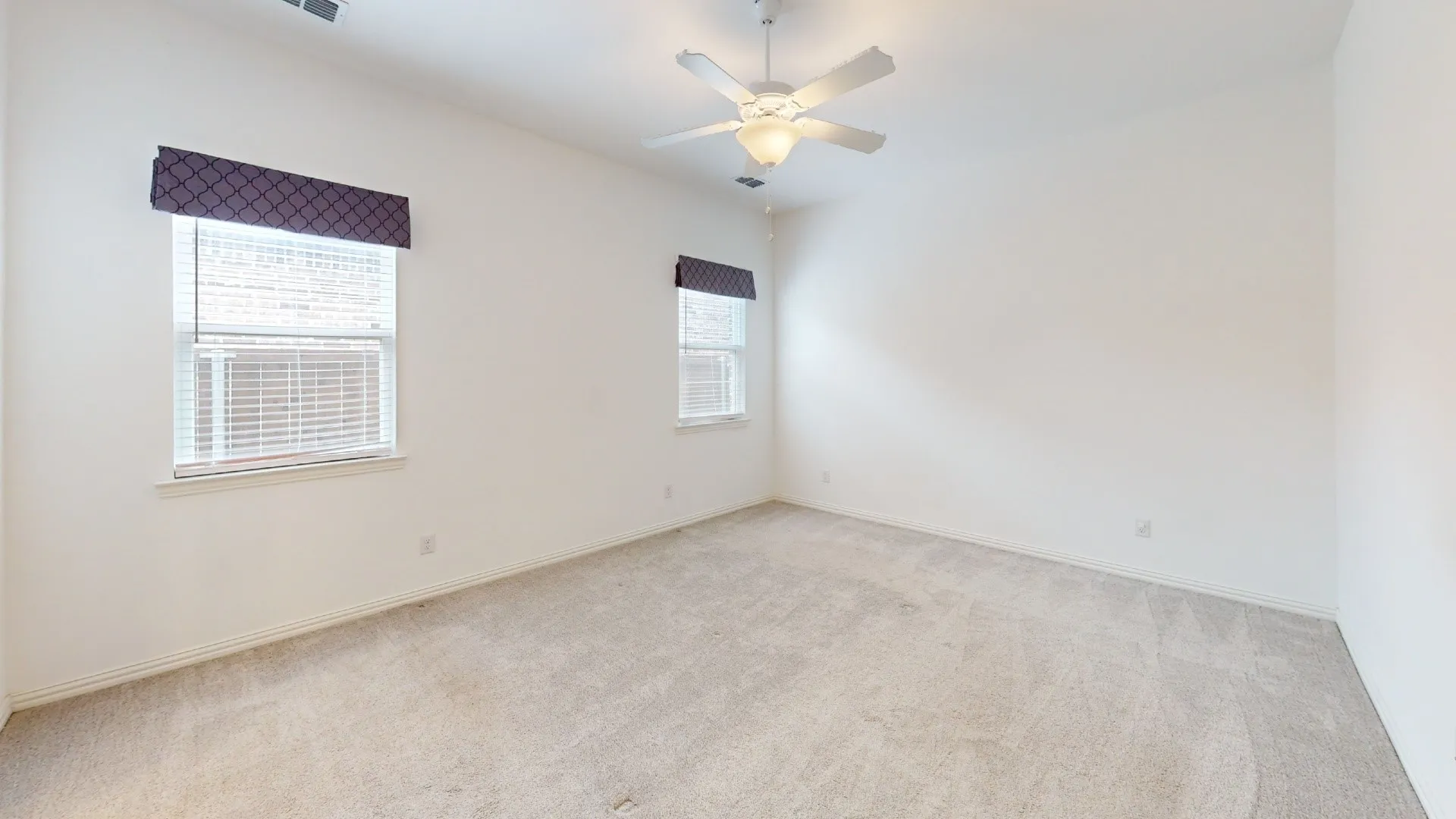 Wall-to-wall carpeting, two windows with blinds, a ceiling fan with integrated lighting, and neutral wall tones