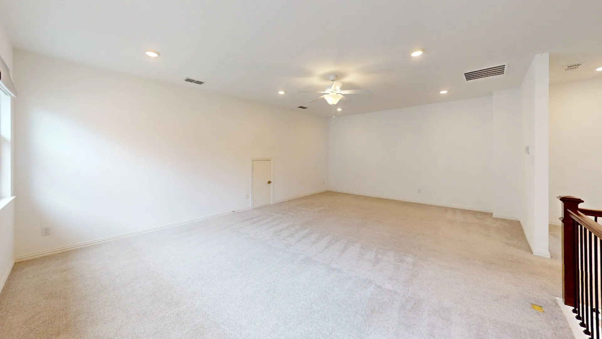 Expansive carpeted area with recessed lighting, a ceiling fan, and a built-in storage door