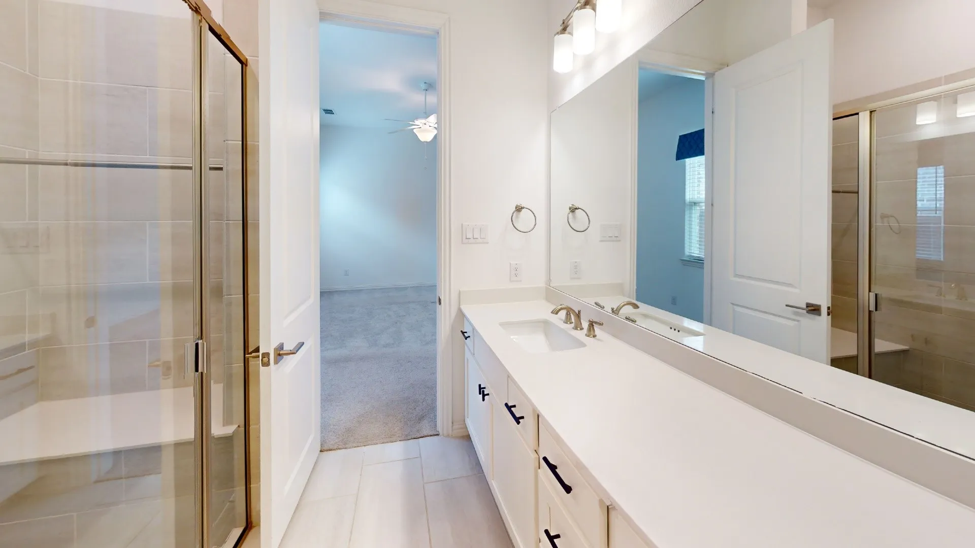 Dual vanity with undermount sinks and wall-mounted faucets, large mirror, walk-in shower with glass enclosure, tiled walls, and built-in bench