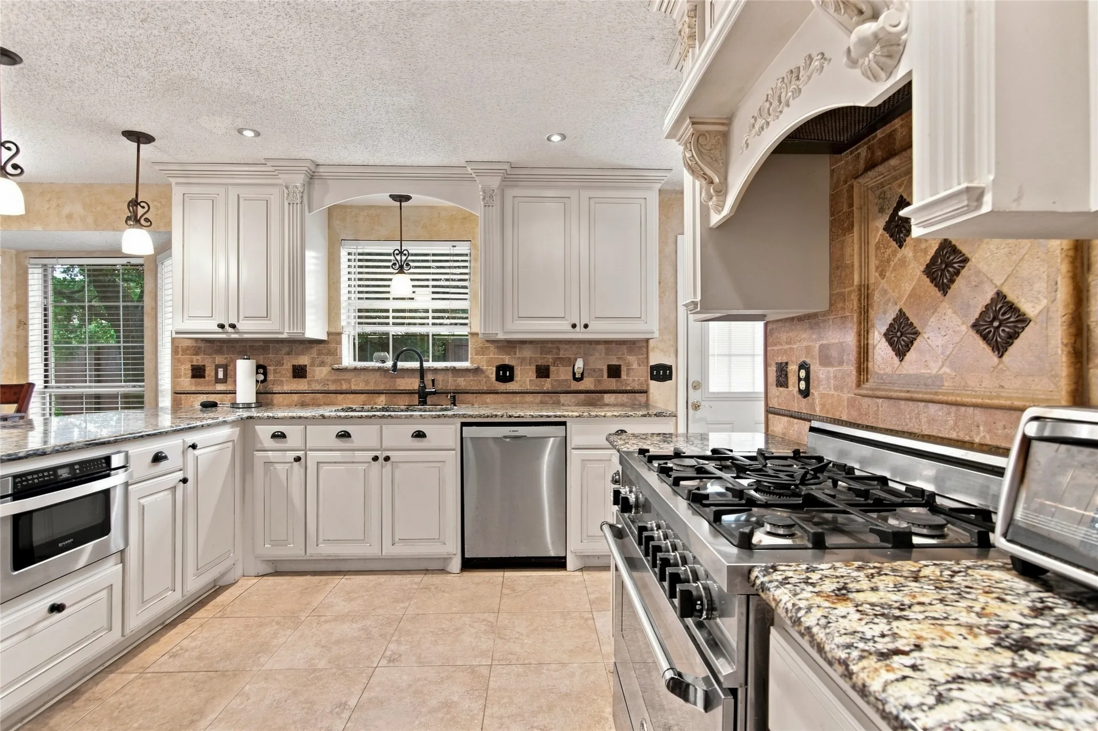 Large custom vent hood, commercial oven and tumbled marble backsplash